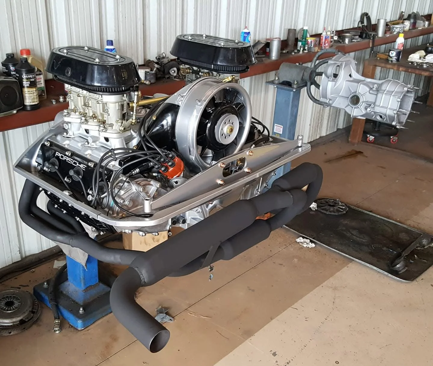 Porsche engine and transmission on a workshop bench with tools and parts.