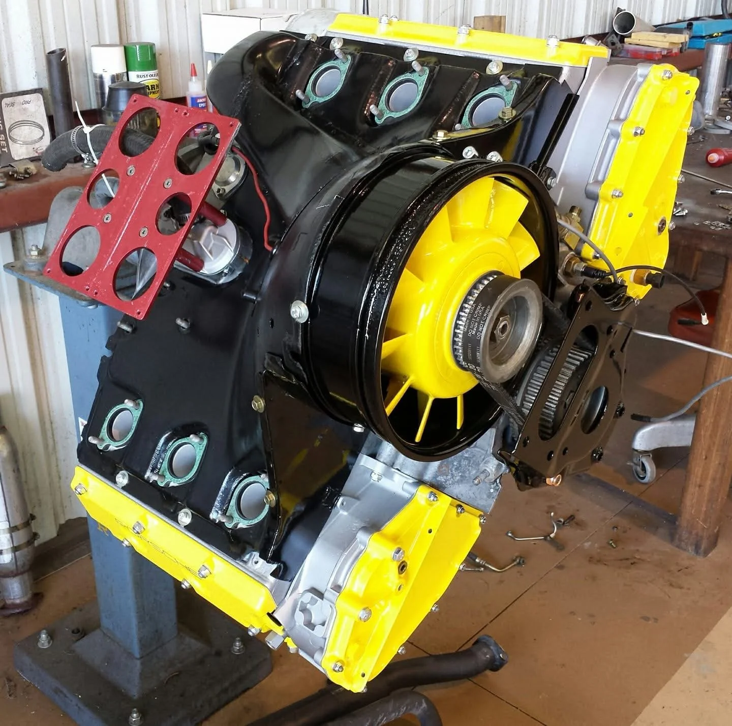Yellow and black rotary engine on a workbench with various tools.