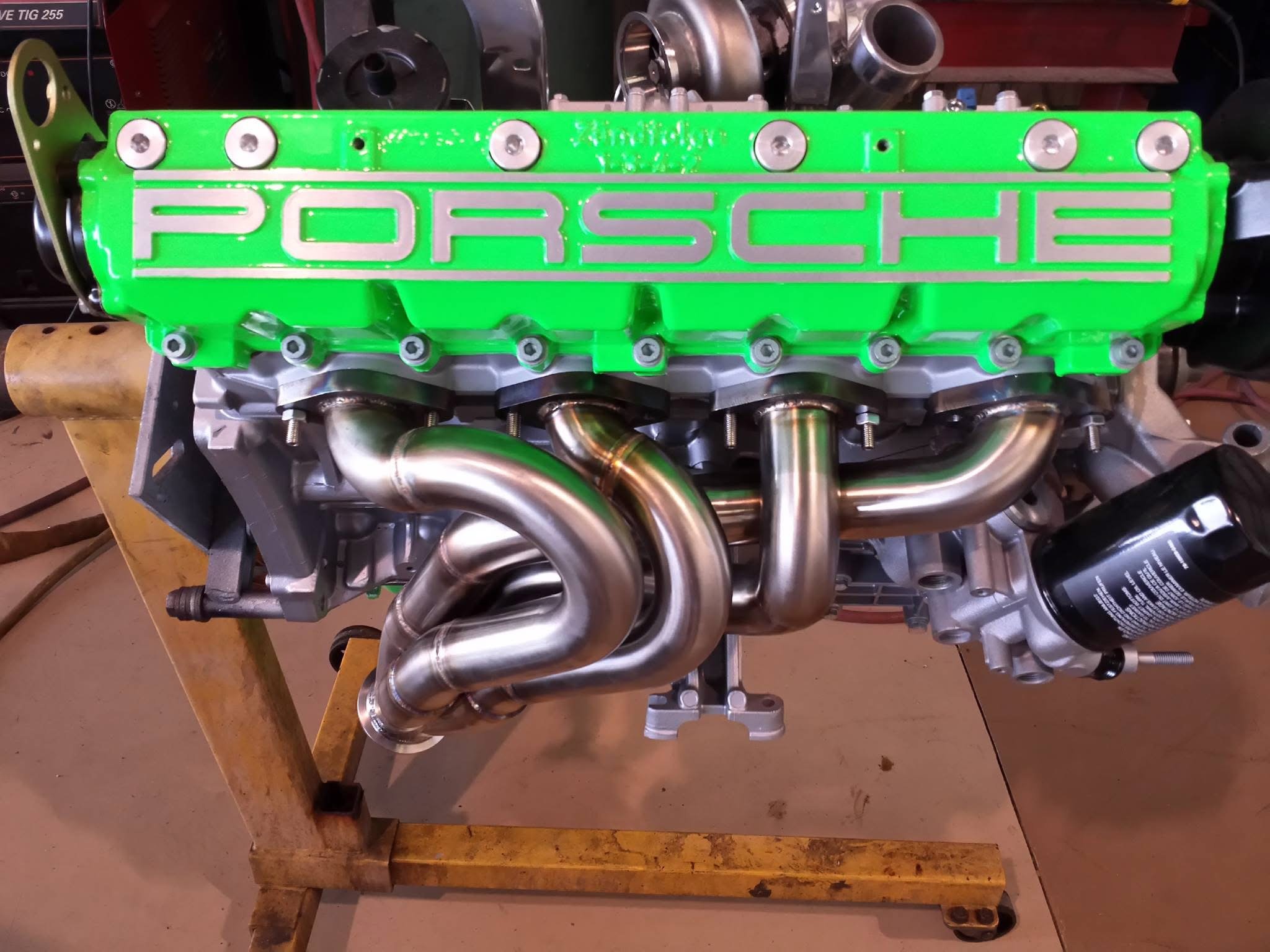 Porsche engine with green valve cover and shiny exhaust pipes