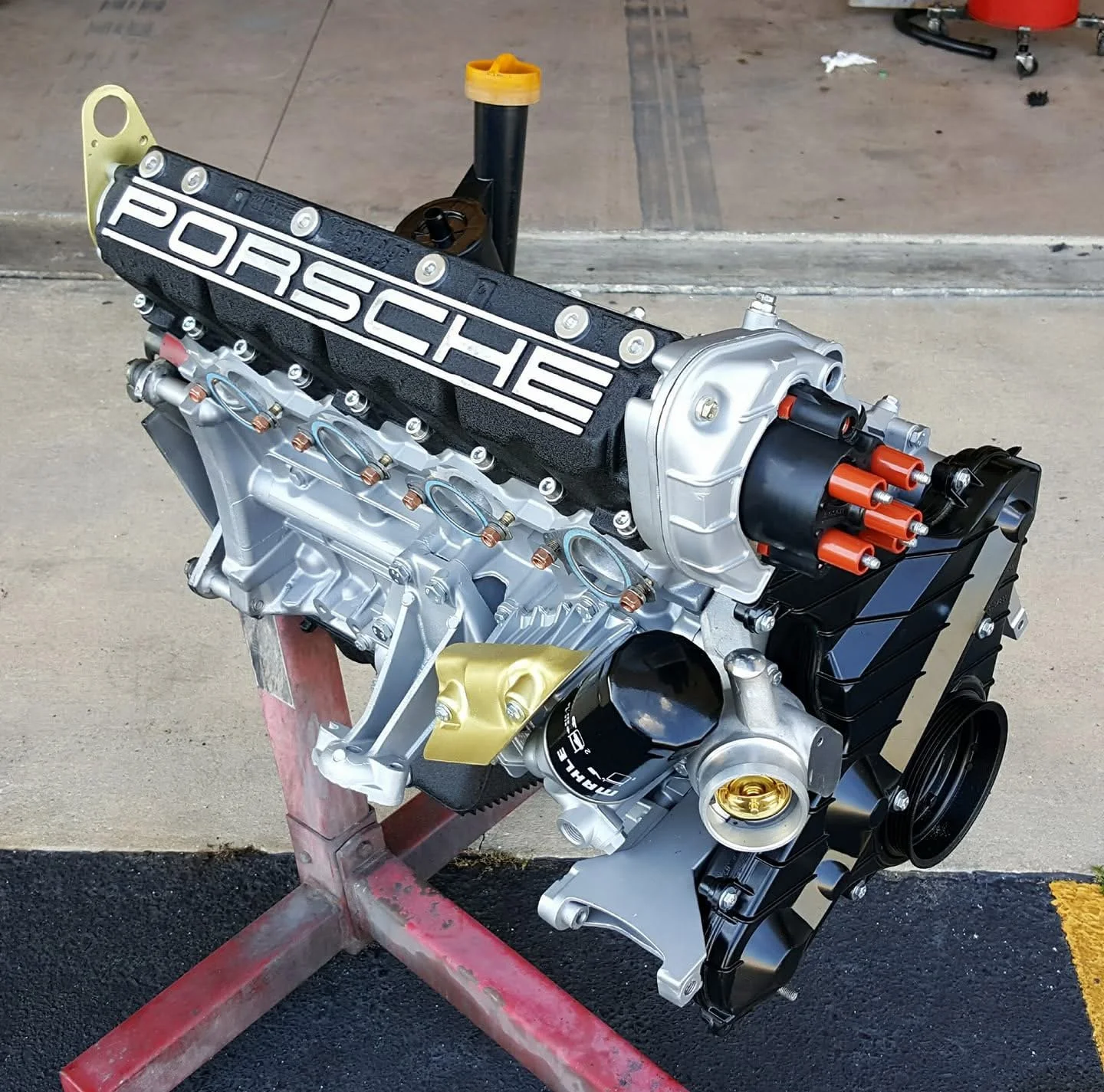 A Porsche engine on a stand in a garage setting.