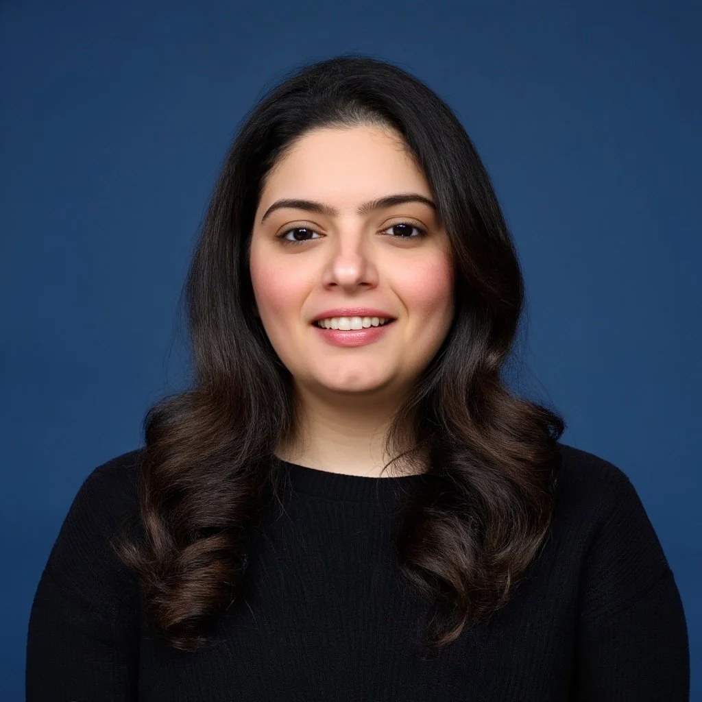 A woman with long, dark hair smiling at the camera against a blue background.