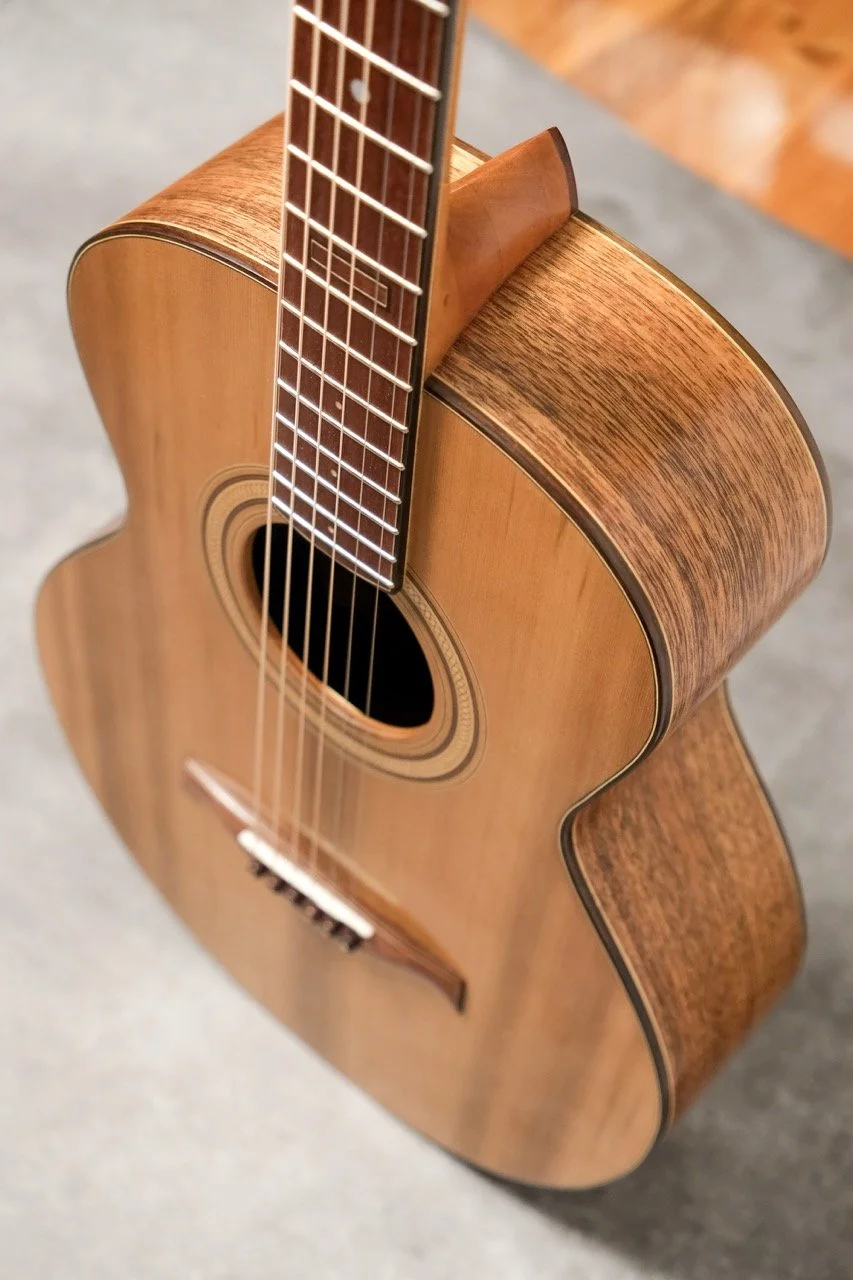 A close-up view of an acoustic guitar showing the body, soundhole, strings, and part of the fretboard.