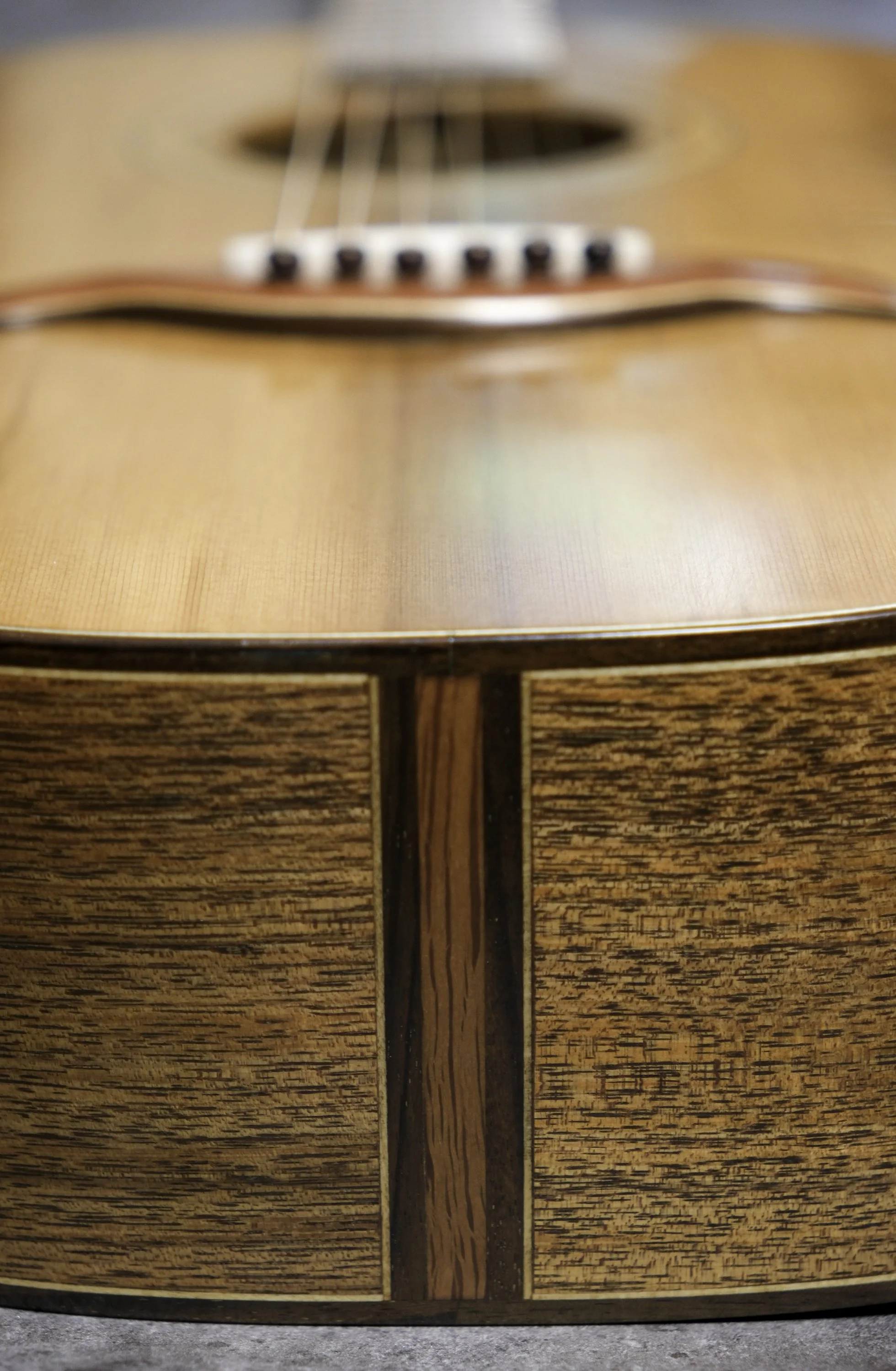 Close-up of a wooden acoustic guitar with a polished finish, showcasing the soundhole and strings.