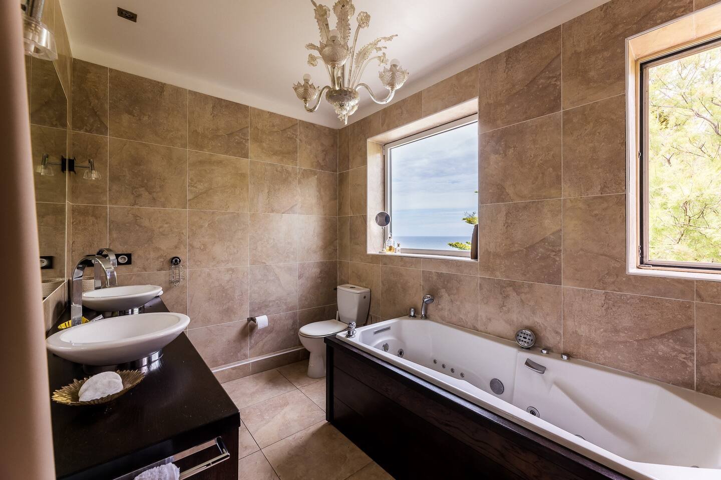 Salle de bain avec baignoire et douche séparée. Double vasque et vue océan