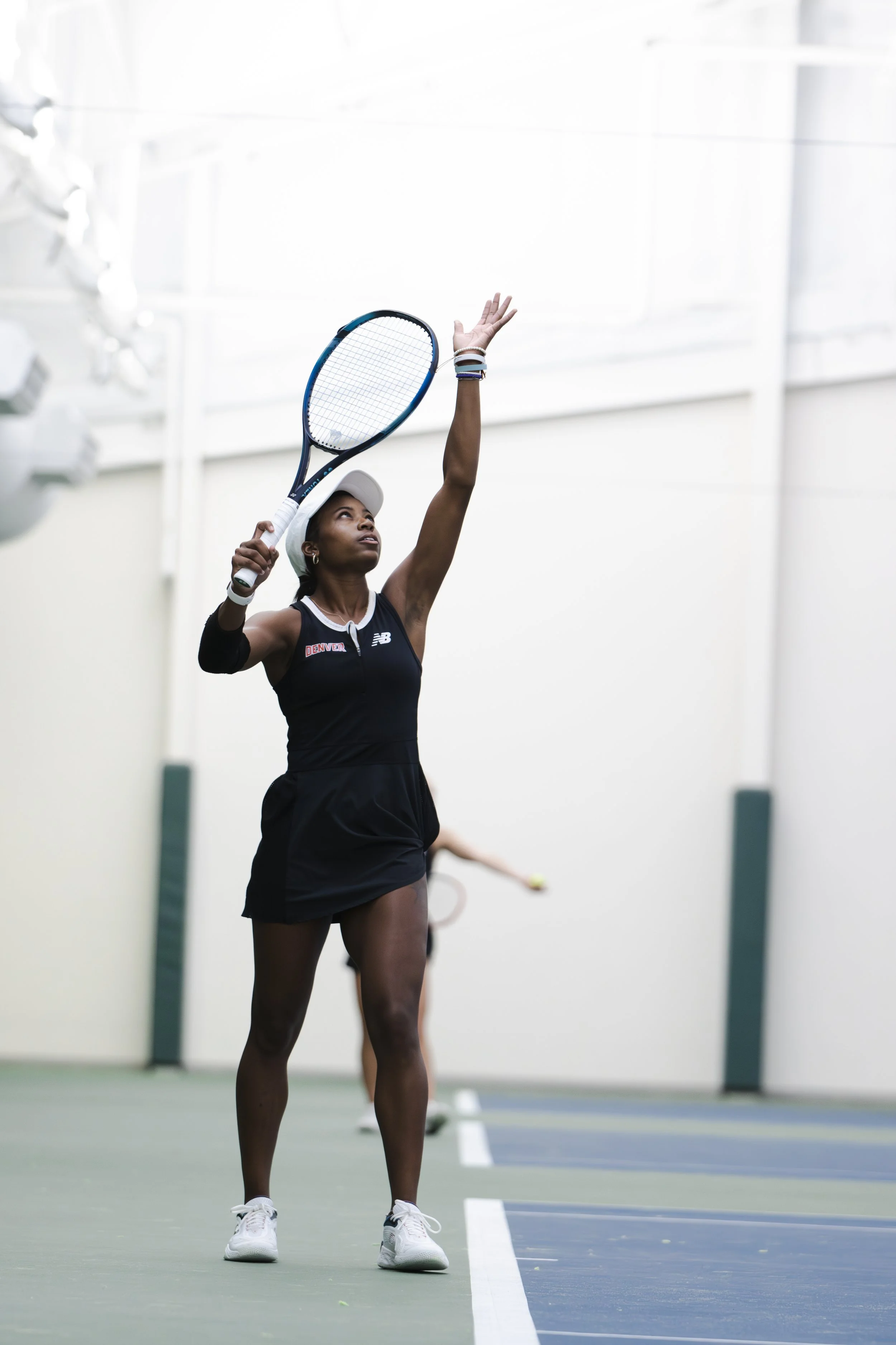 Female tennis player in athletic attire serving on indoor court.