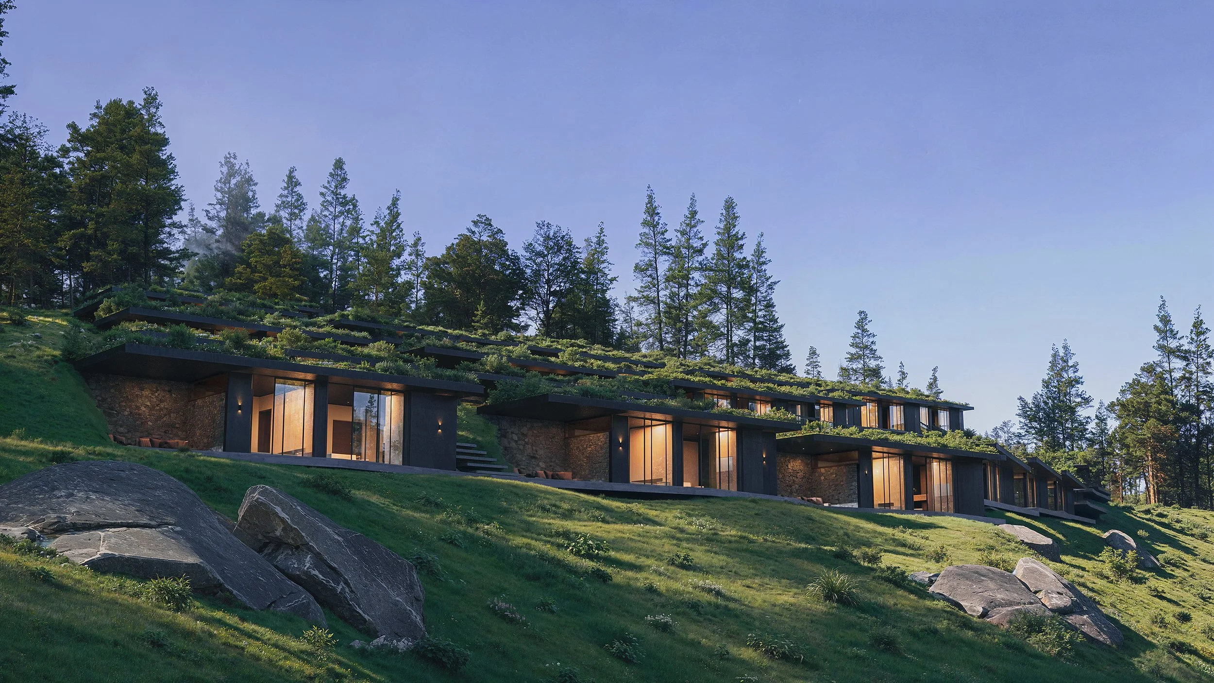 Modern house built into a hillside with large glass windows, surrounded by pine trees and rocks, during the daylight.