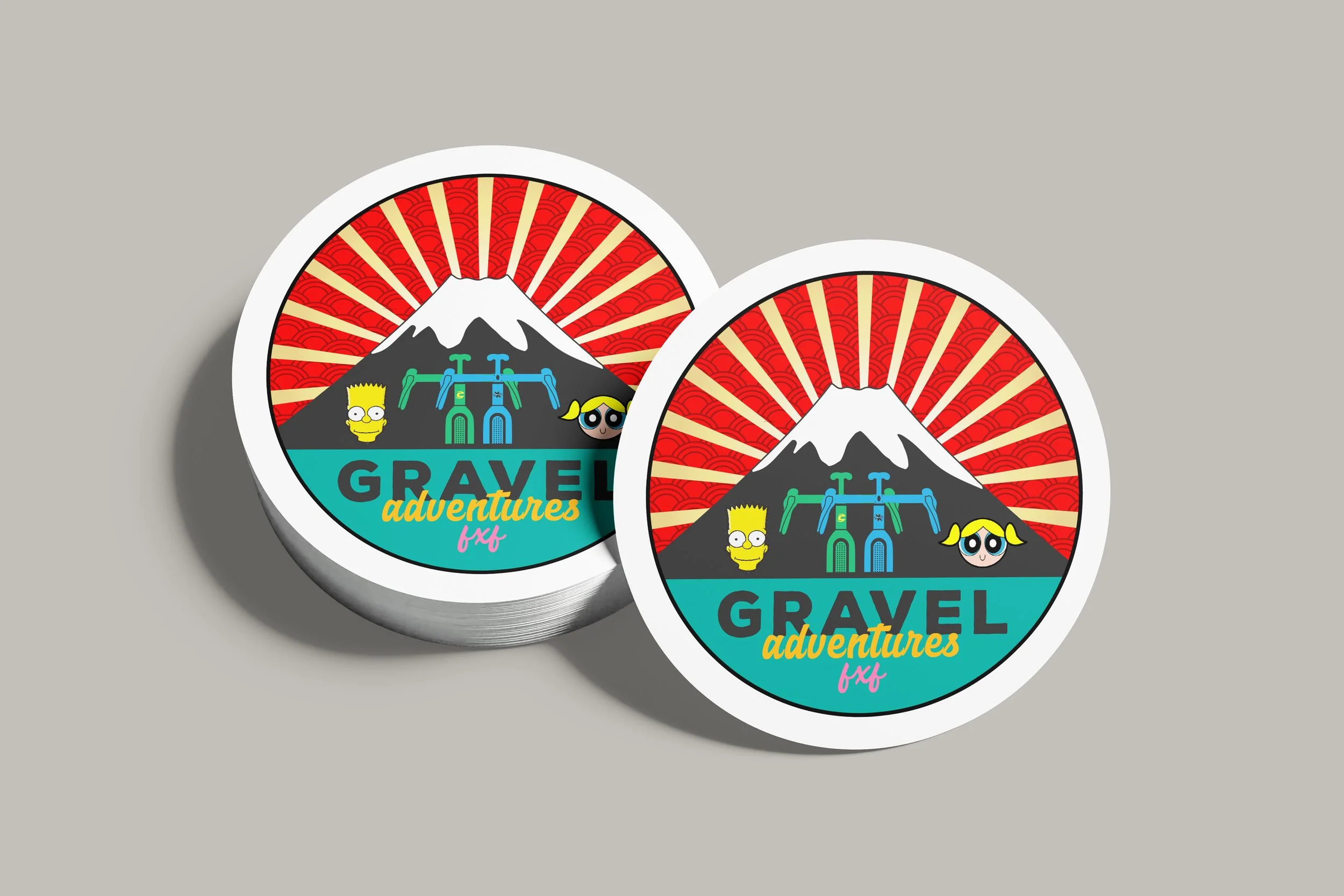 A stack of round stickers featuring a design with a stylized mountain, red rays, cartoon characters, and the text 'Gravel Adventures fx4'.