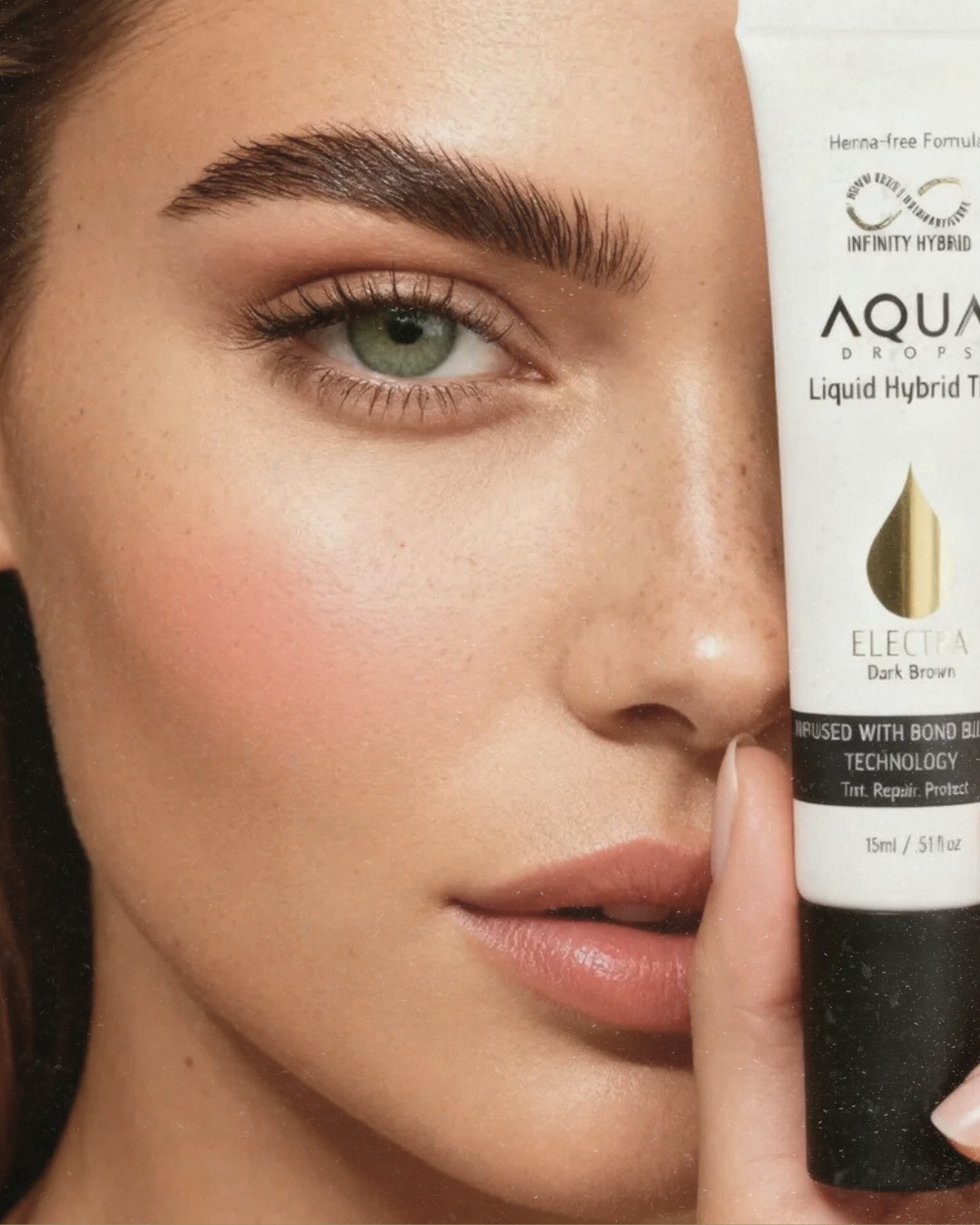Close-up of a woman holding a tube of Aqua Drops Liquid Hybrid Tinted Moisturizer with her finger near her face, showing her eye, nose, and lips.