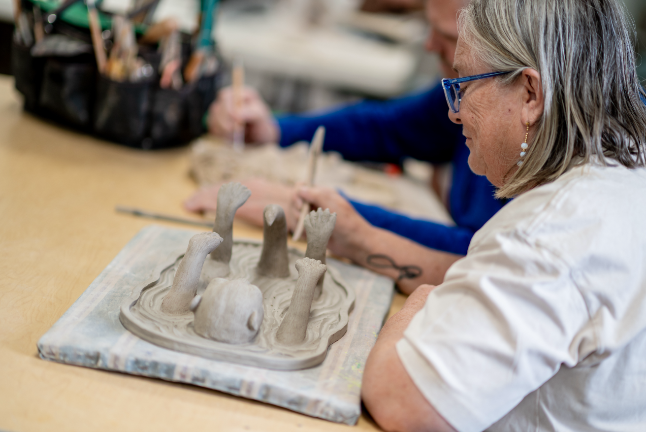 Person sculpting clay art in ceramics class