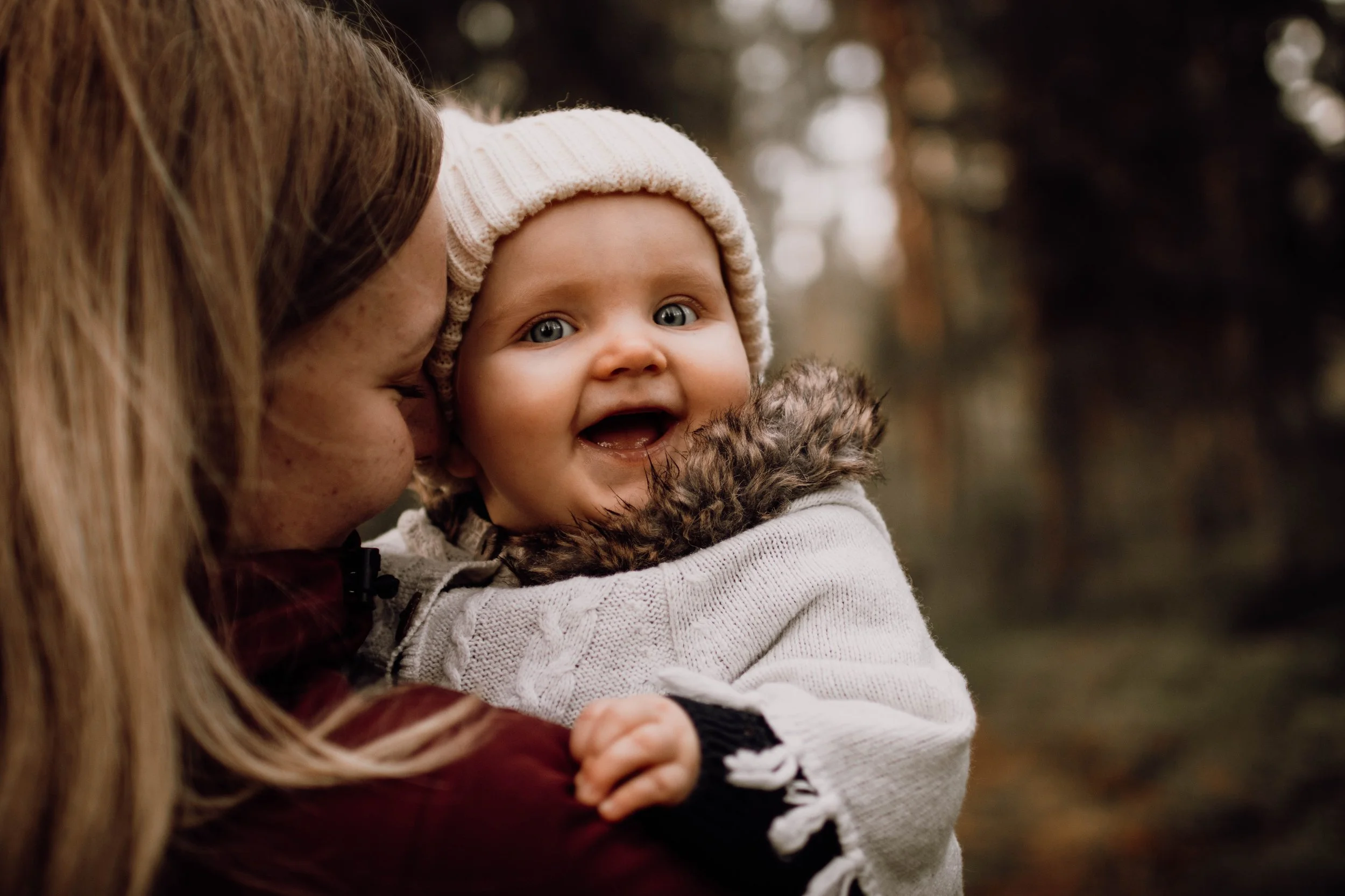 En mamma håller sin bebis och lägger mjukt pannan mot hennes kind medan hon blundar, båda lyser av lycka