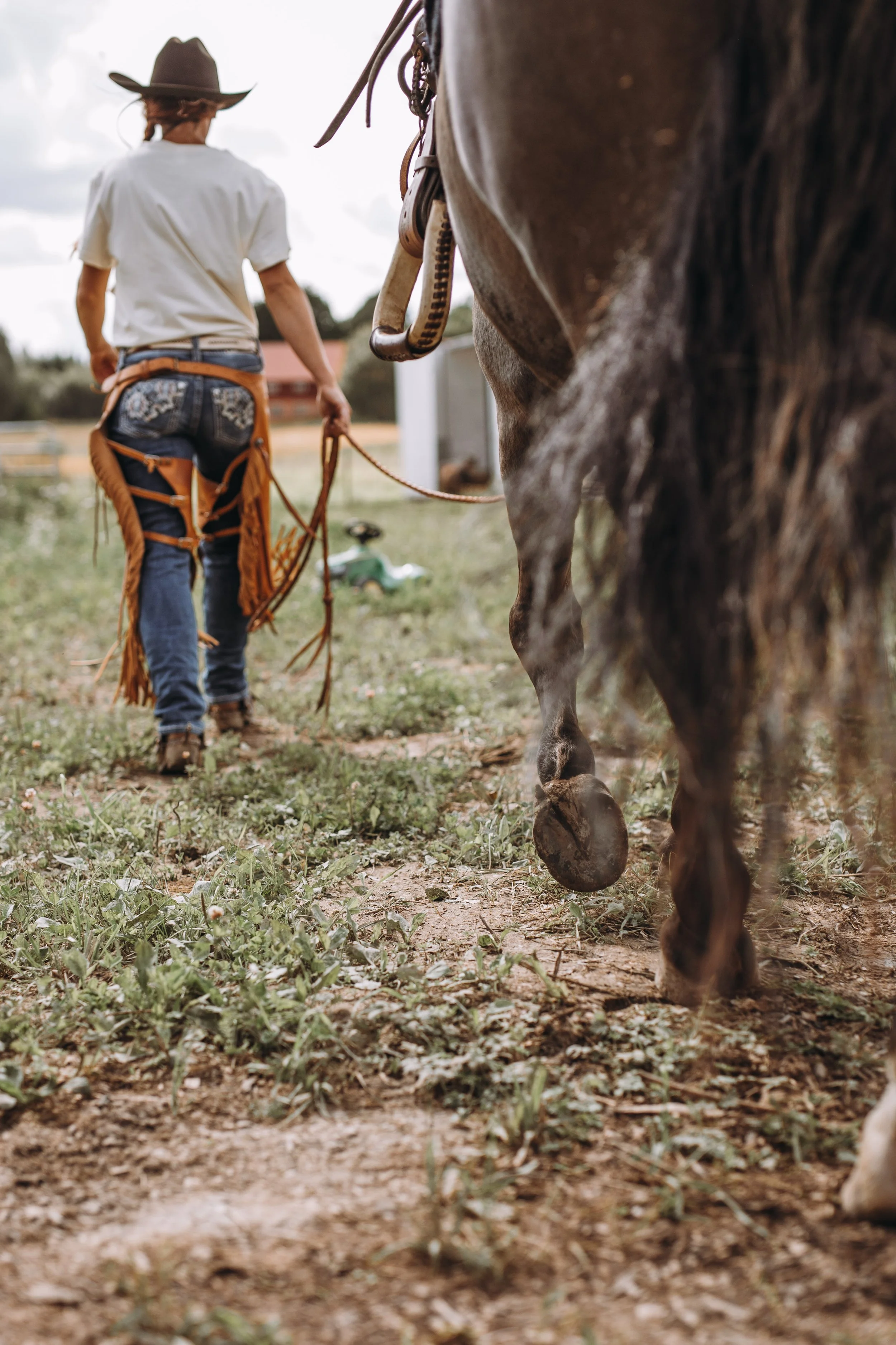 En cowgirl som leder sin häst bort från kameran