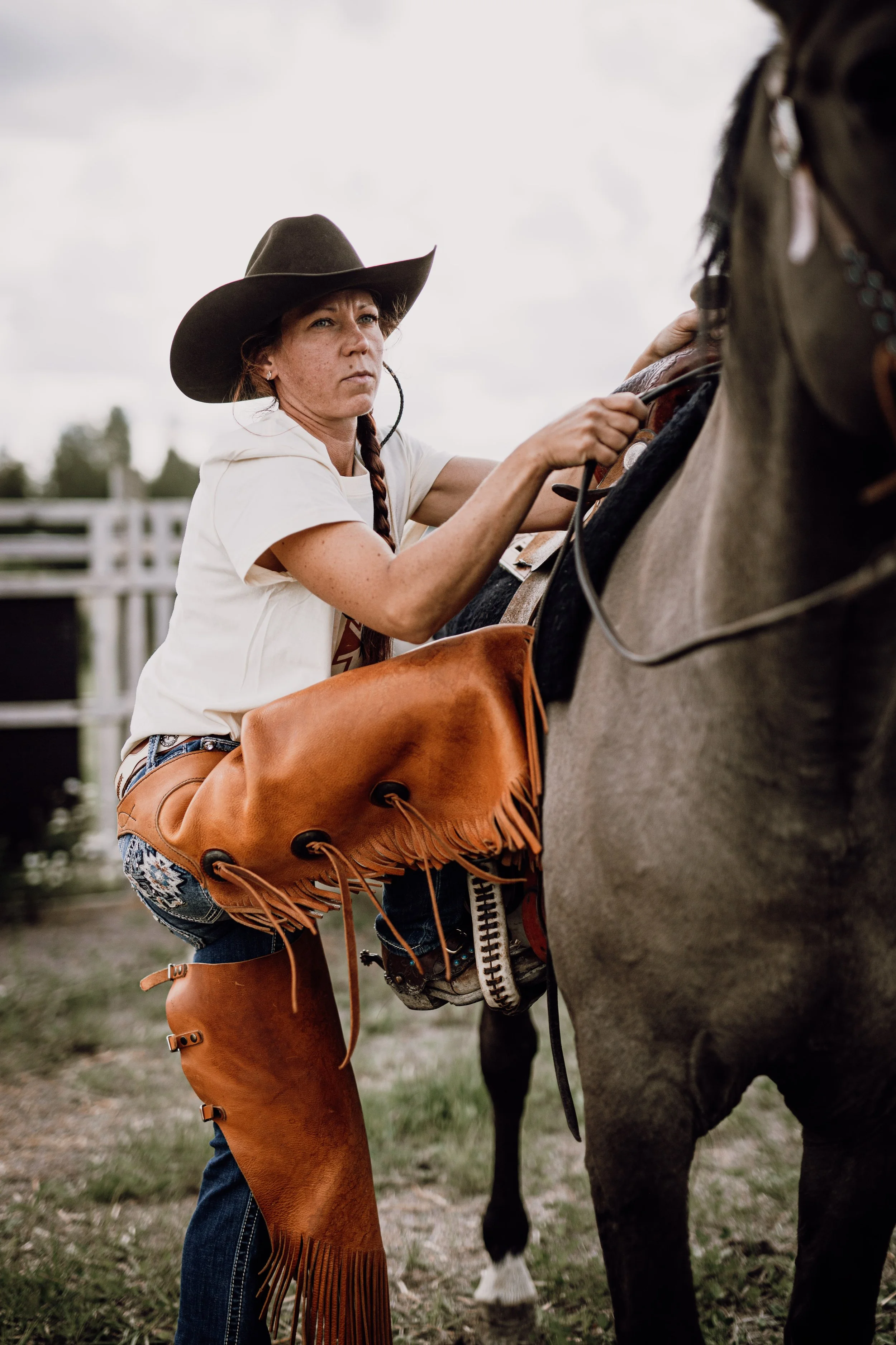 En cowgirl som precis ska sitta upp på sin häst