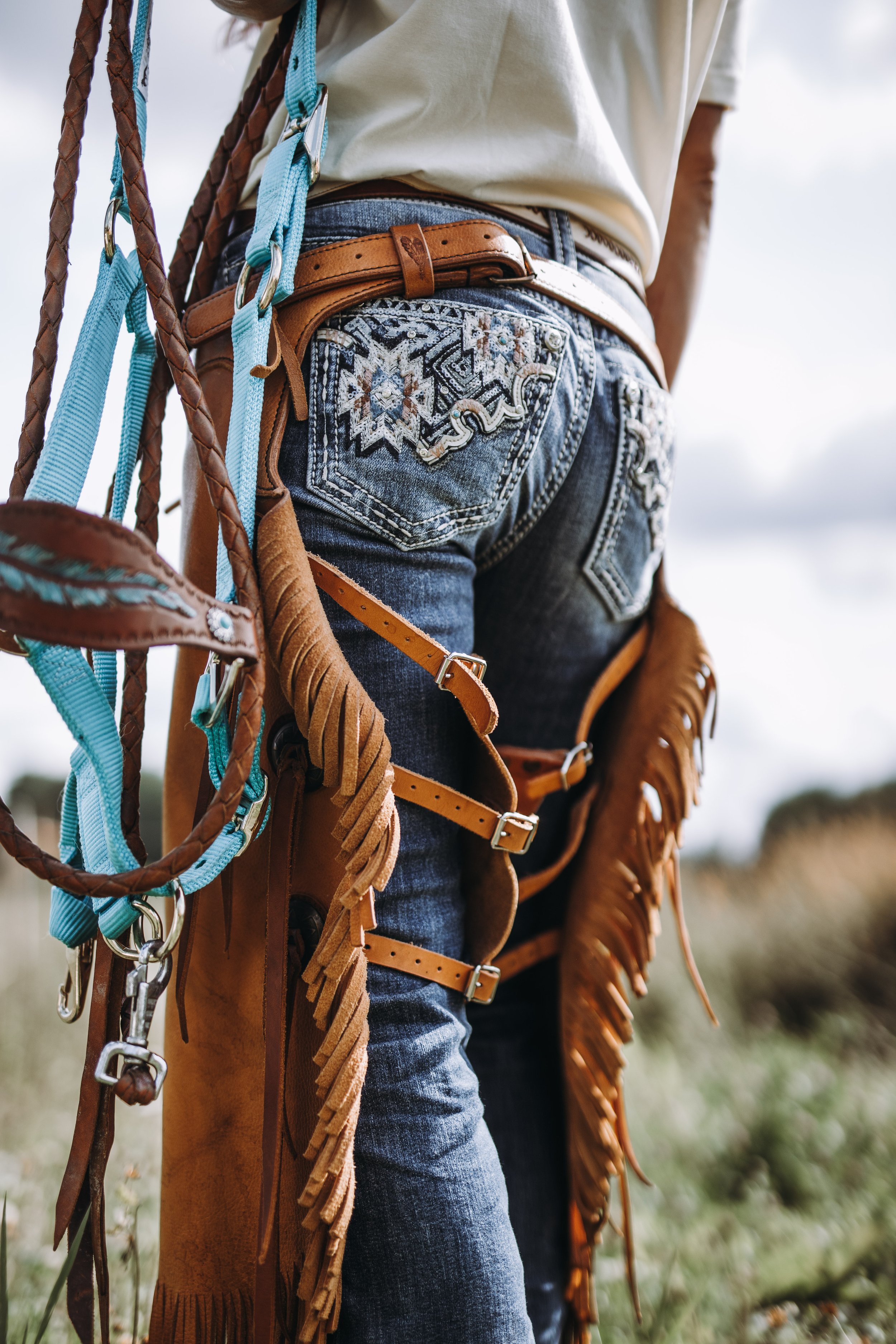 En detaljbild på rumpan på et par jeans med chaps och grimma i handen