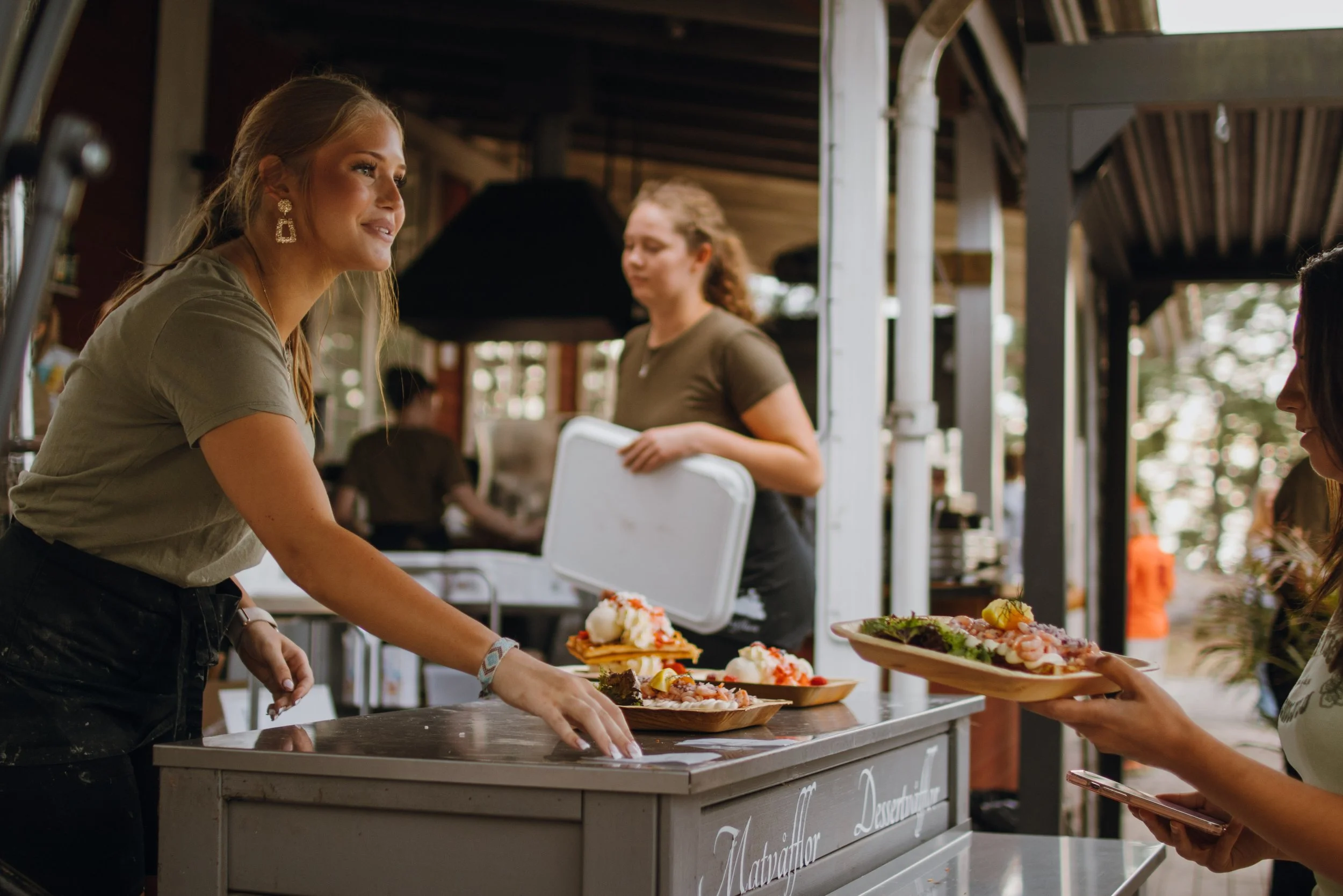 Kvinna som säljer mat till kund i utomhusmiljö.