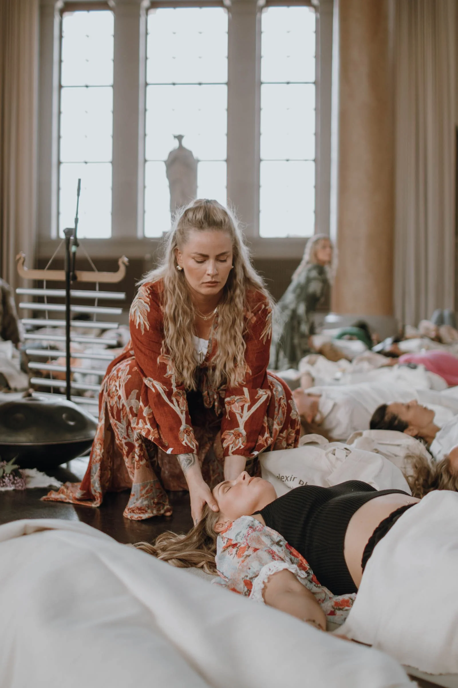 En kvinna ger första hjälpen till en annan kvinna som ligger på golvet i ett rum med många andra människor som sover.