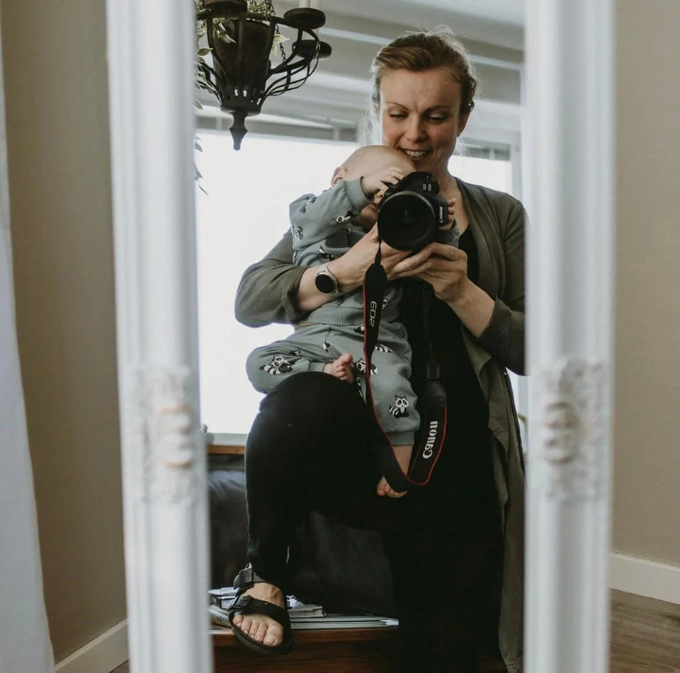 En mamma tar ett foto på sig själv i spegeln med kameran framför sig, i knät har hon sin 9-månaders bebis som gärna hjälper till