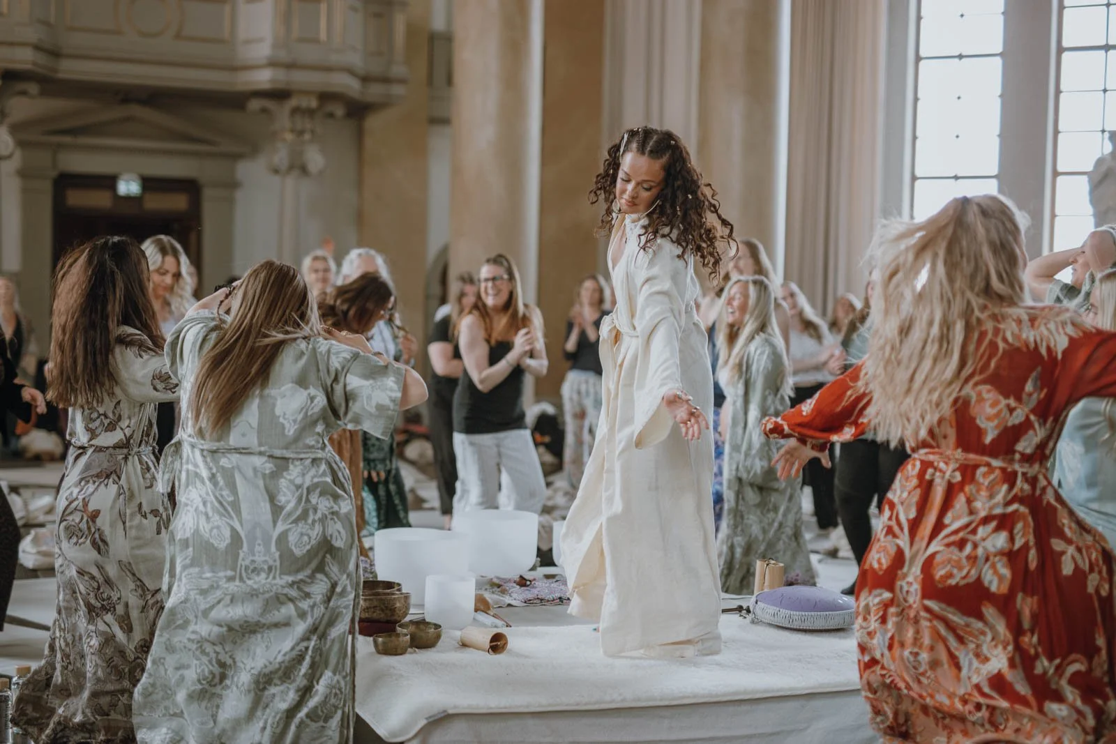 Kvinnor som dansar och har roligt i ett stort, elegant rum med höga fönster och klassisk inredning.