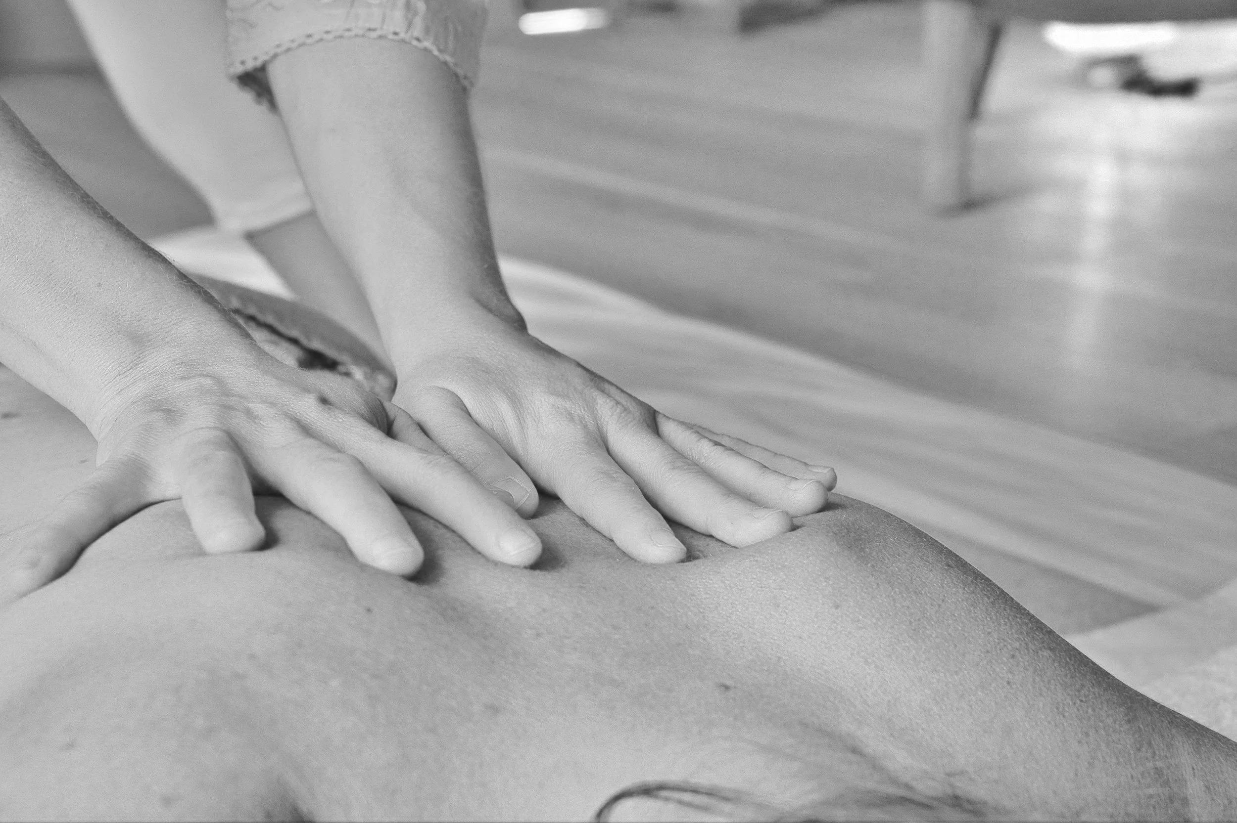 Massage thérapeutique sur un dos humain, avec des mains appliquant une pression.