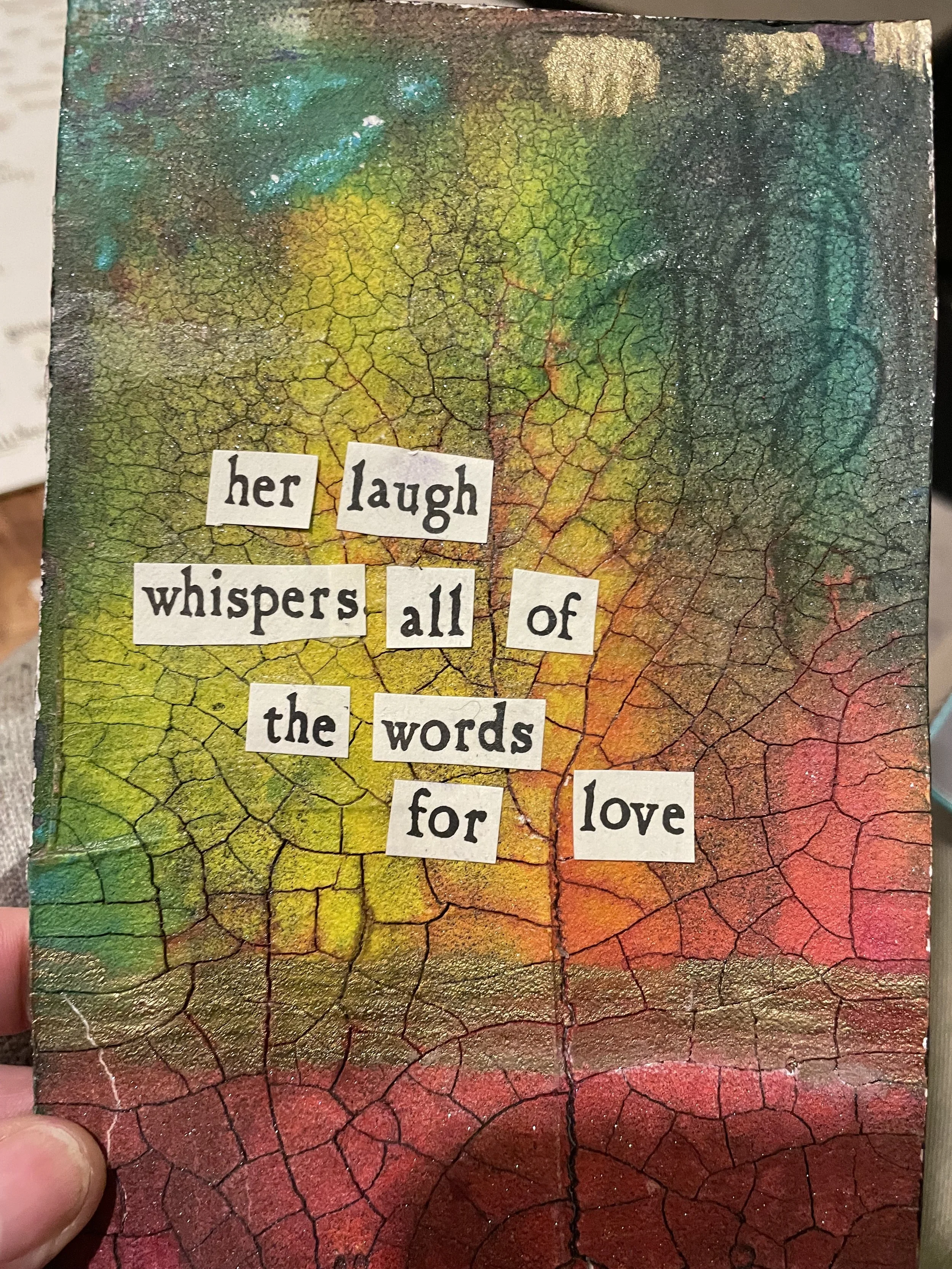mixed media crackle painitng in rainbow colors reading "her laugh whispers all of the words for love"