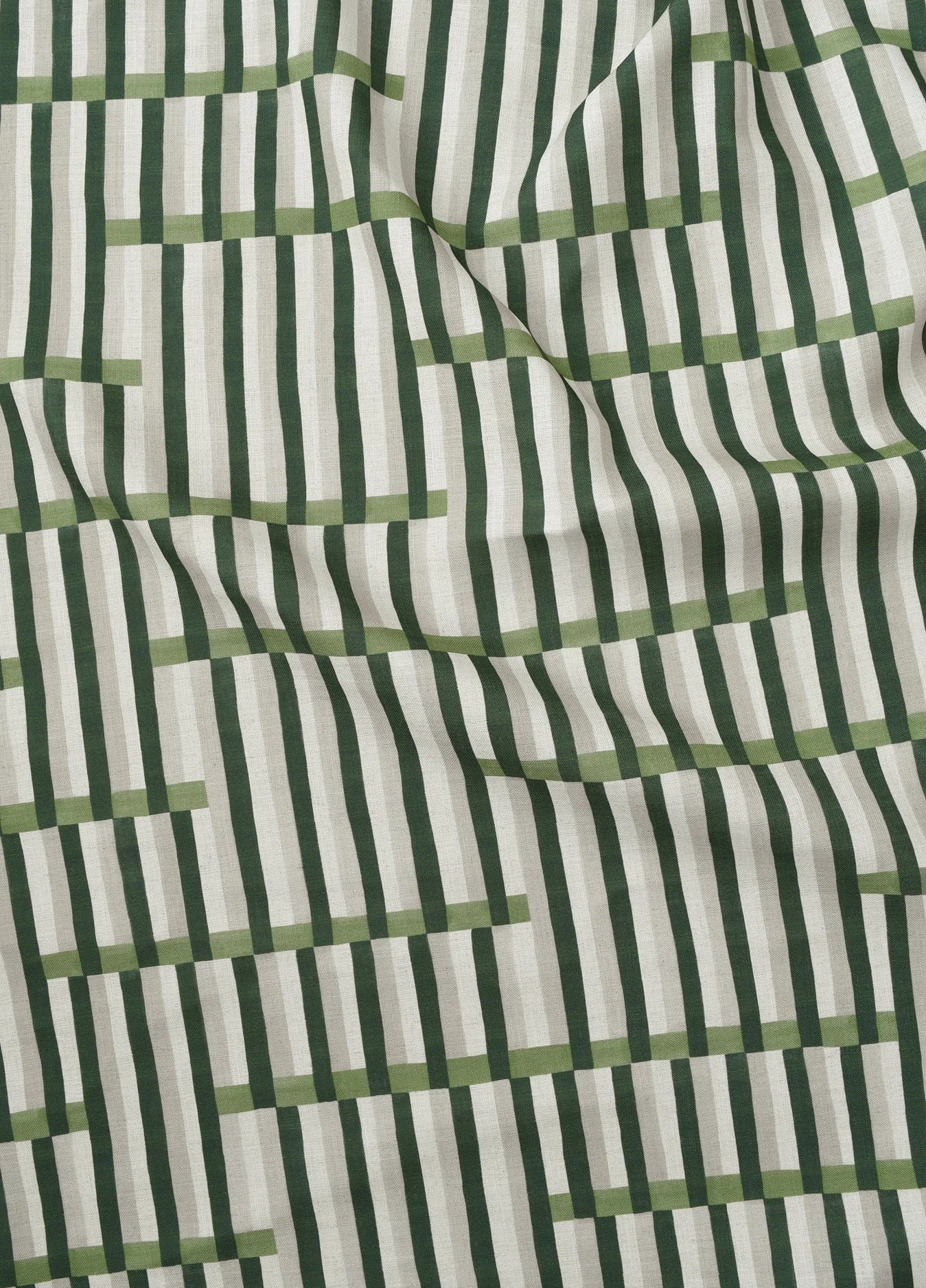 Close-up view of a fabric with a white background featuring a striped pattern of alternating green and black lines.