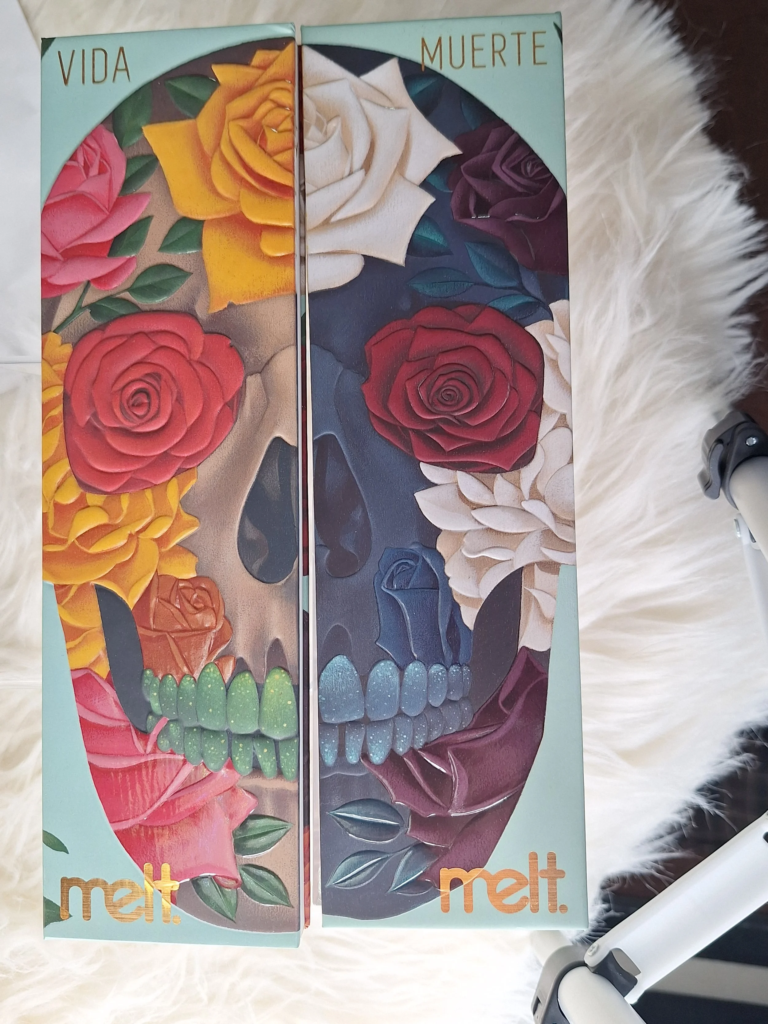 A box with a split design showing a human skull illustration, decorated with colorful roses, leaves, and the words 'VIDA' and 'MUERTE' at the top. The brand name 'melt.' is at the bottom.