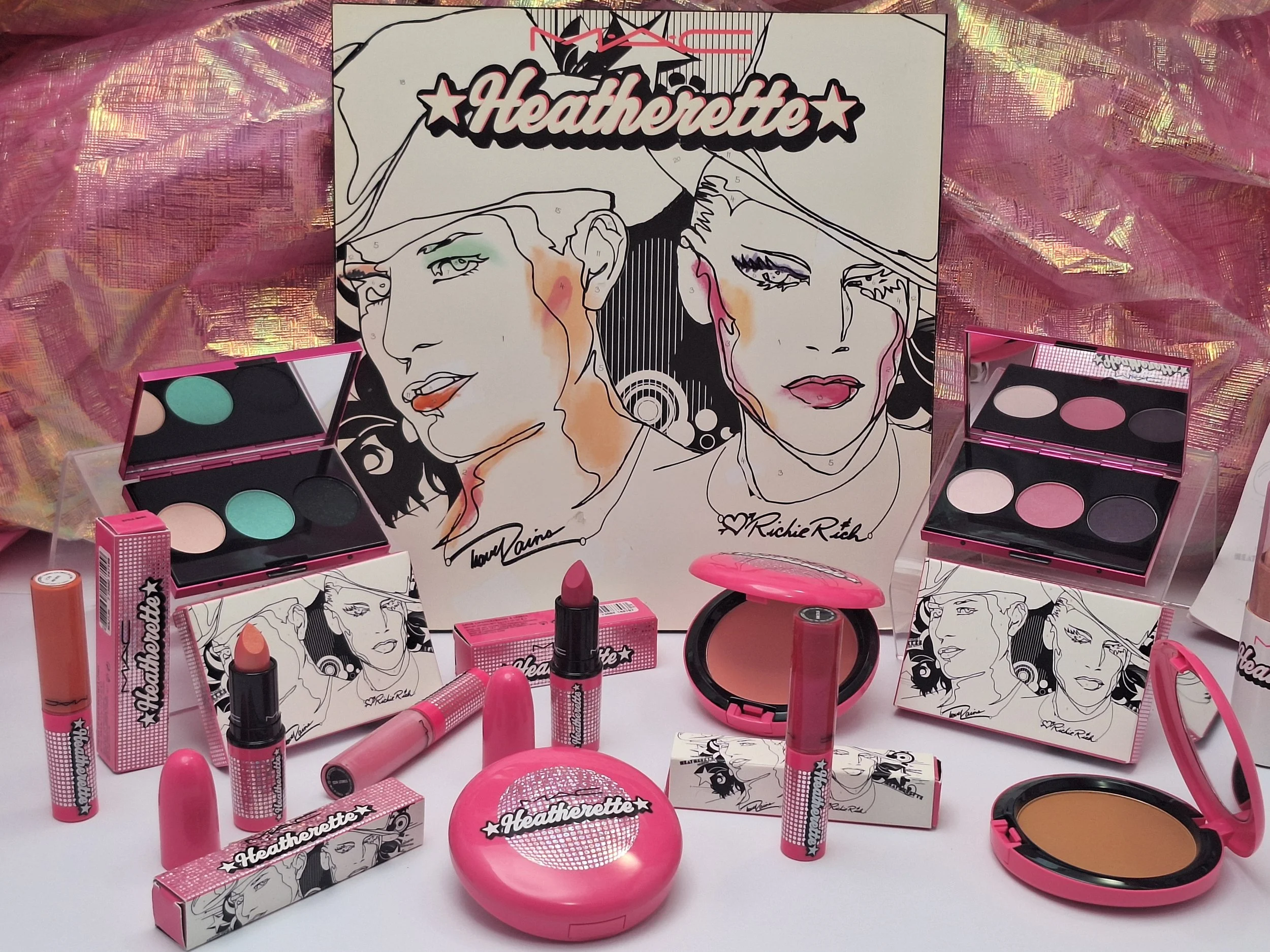 MAC Heatherette full collection flat lay including lipsticks, eyeshadow trios, display inserts, and nail polish with rare coloring book background.