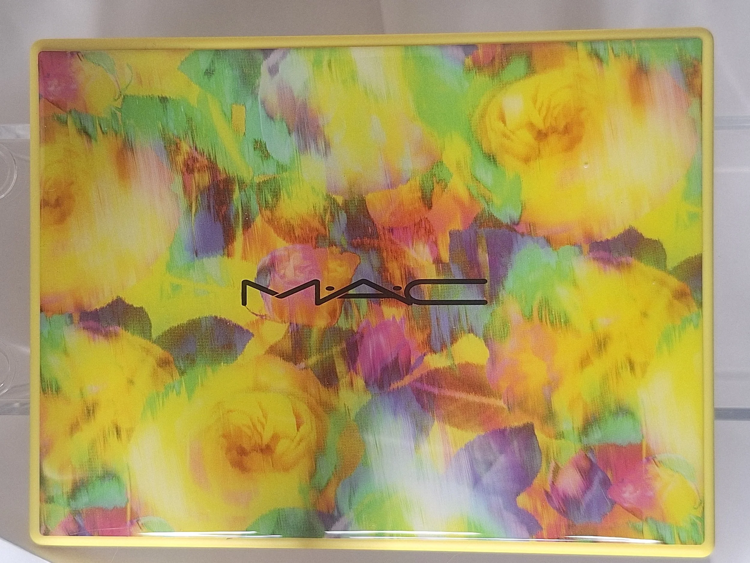 A colorful box with an abstract floral watercolor design in yellow, pink, purple, green, and orange. The MAC logo is centered on the box.