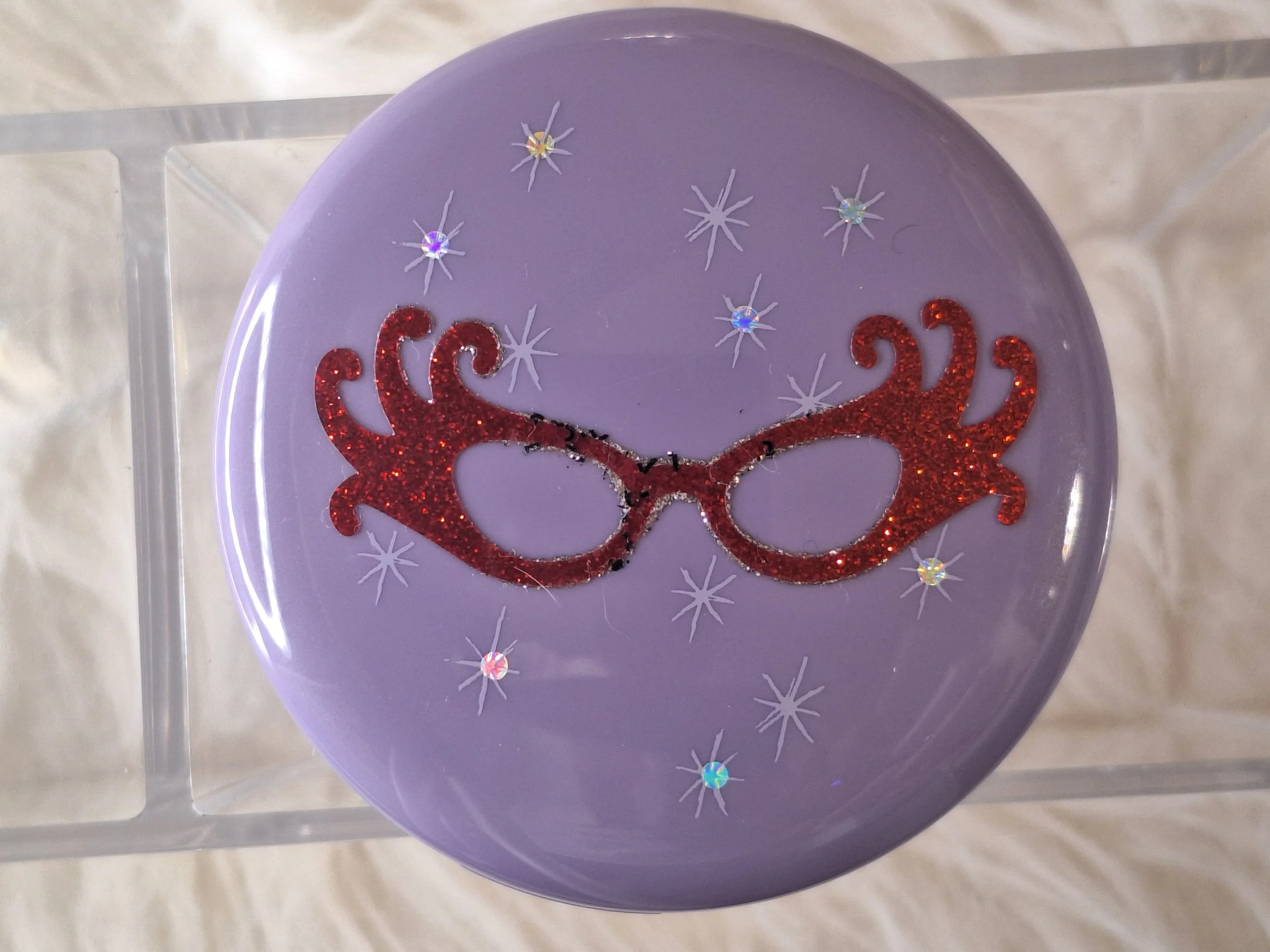 "M·A·C Dame Edna beauty powder, eyeshadows, and signature packaging from Sparkle Society vault."
