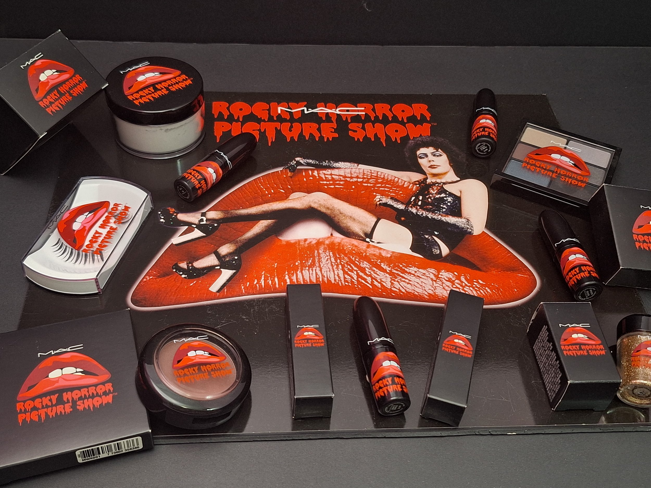 Close-up of M·A·C Rocky Horror lipsticks, glitters, blushes, and store display board