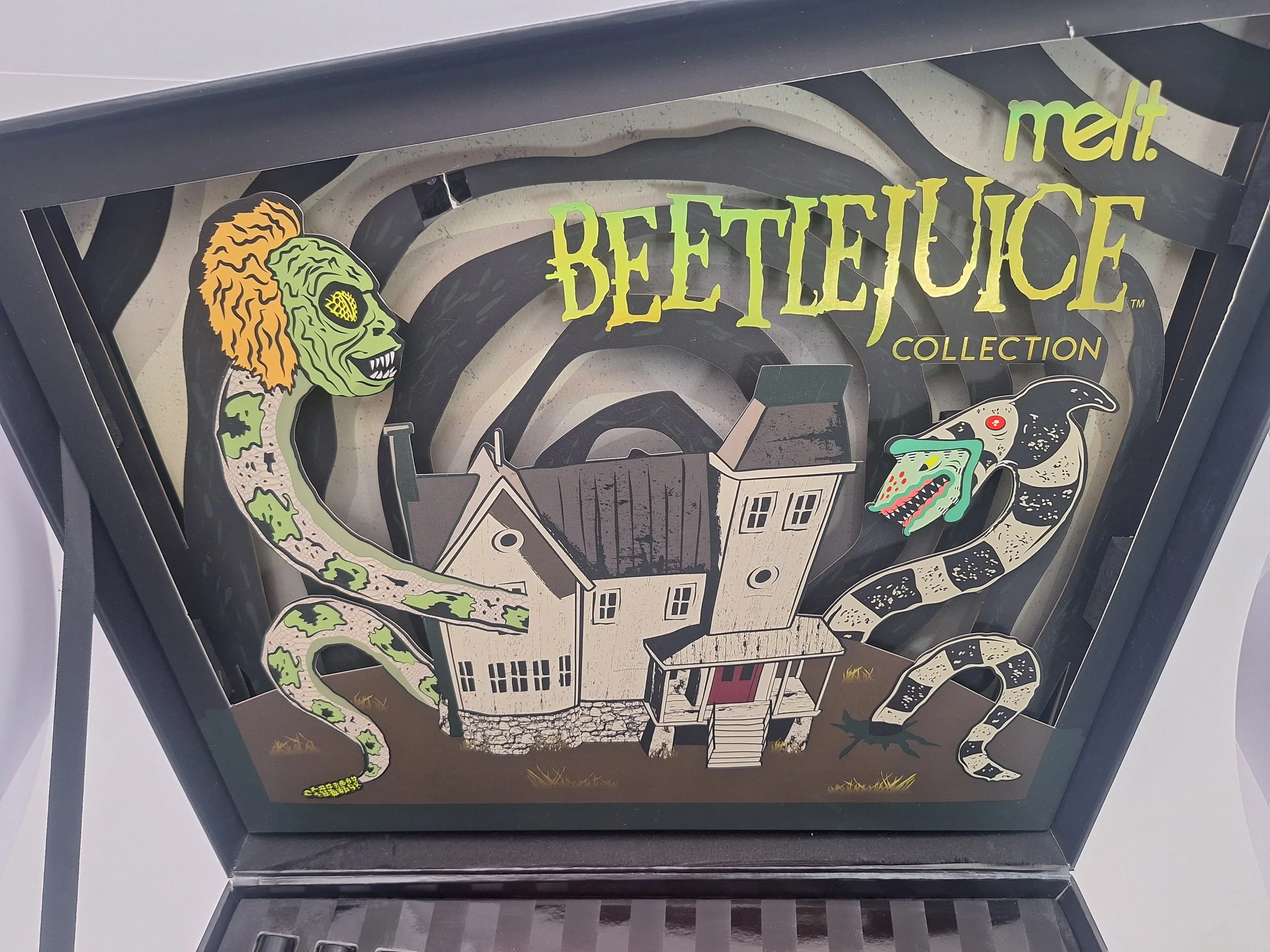 A decorative Halloween-themed box featuring illustrations of Frankenstein's monster and a dragon, a spooky house, and the words 'melt! Beetlejuice Collection'.