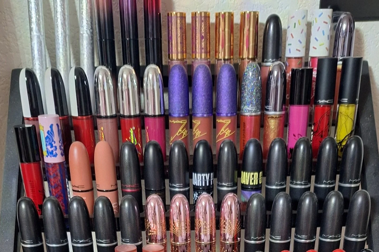 A collection of various lipstick tubes organized on a black display rack.
