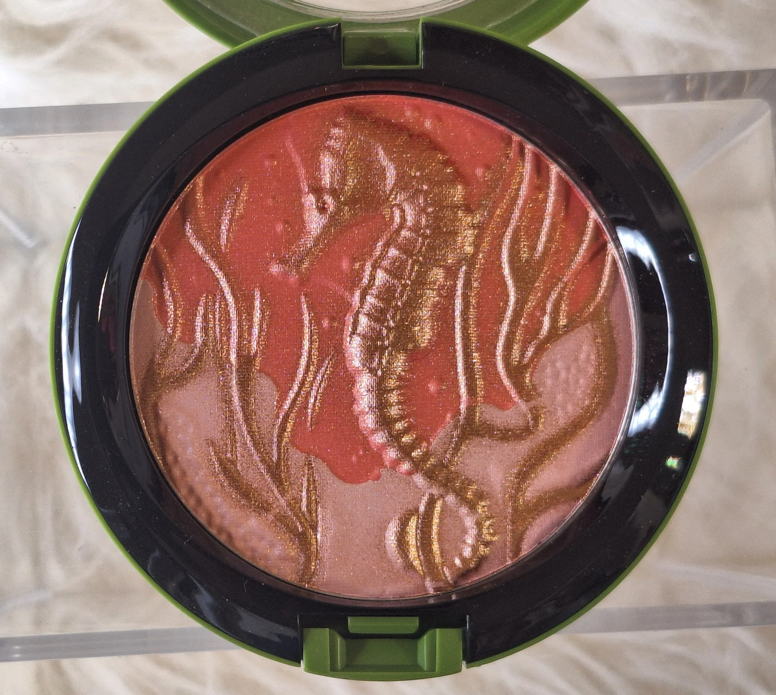 Close-up of M·A·C Marine Life Highlight Powder showing embossed seahorse and coral design in peach and gold tones from the 2010 To the Beach collection