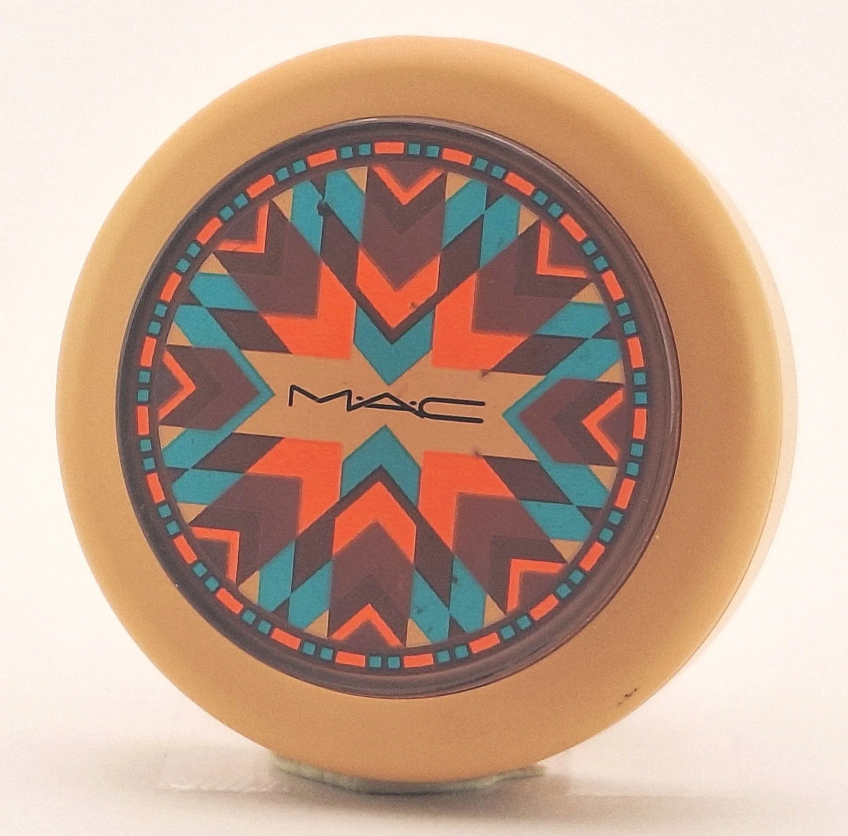 A makeup compact by MAC with a colorful geometric pattern on the top.
