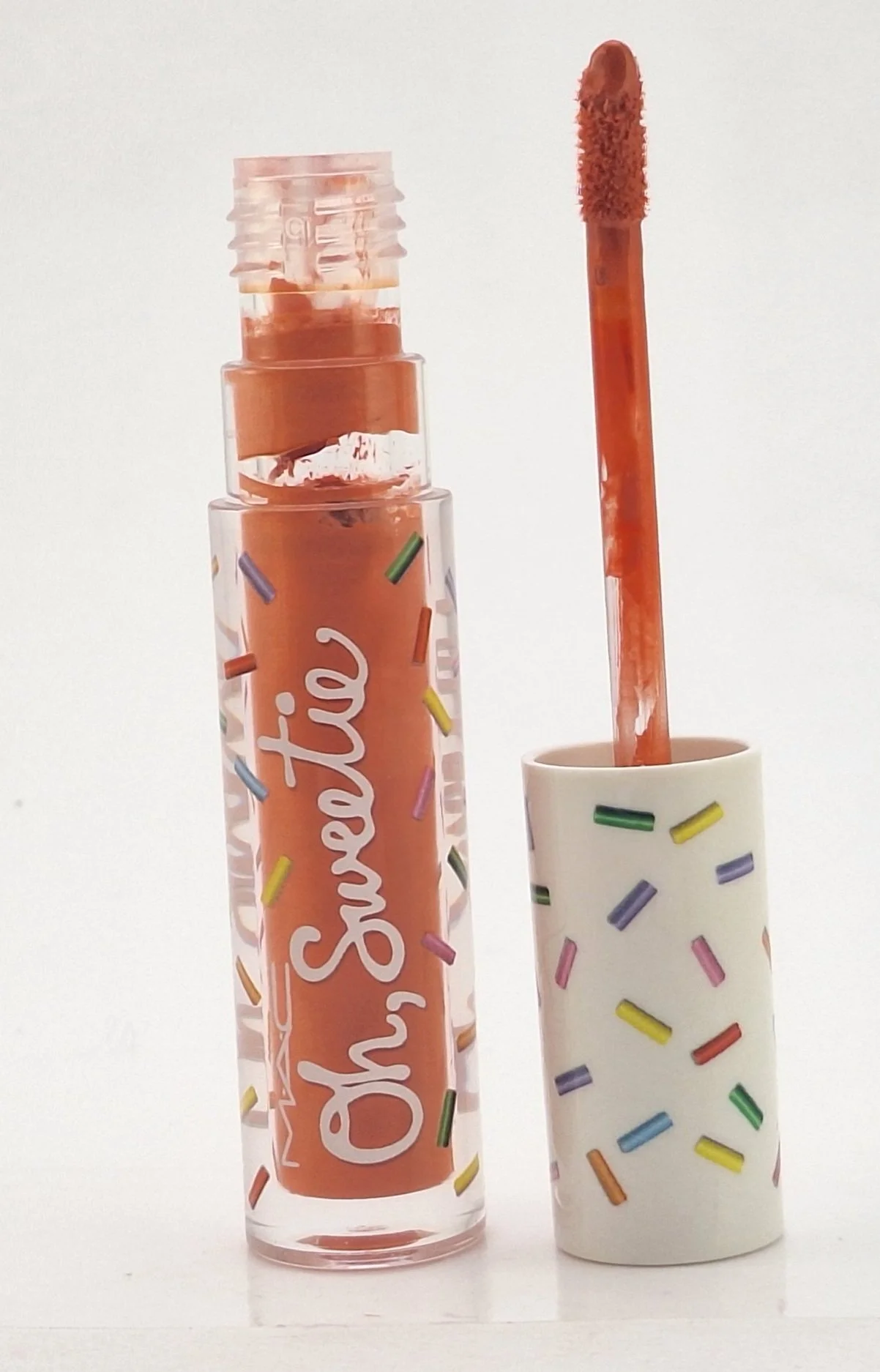 Close-up of M·A·C Oh, Sweetie Lipgloss packaging with vibrant, candy-colored caps