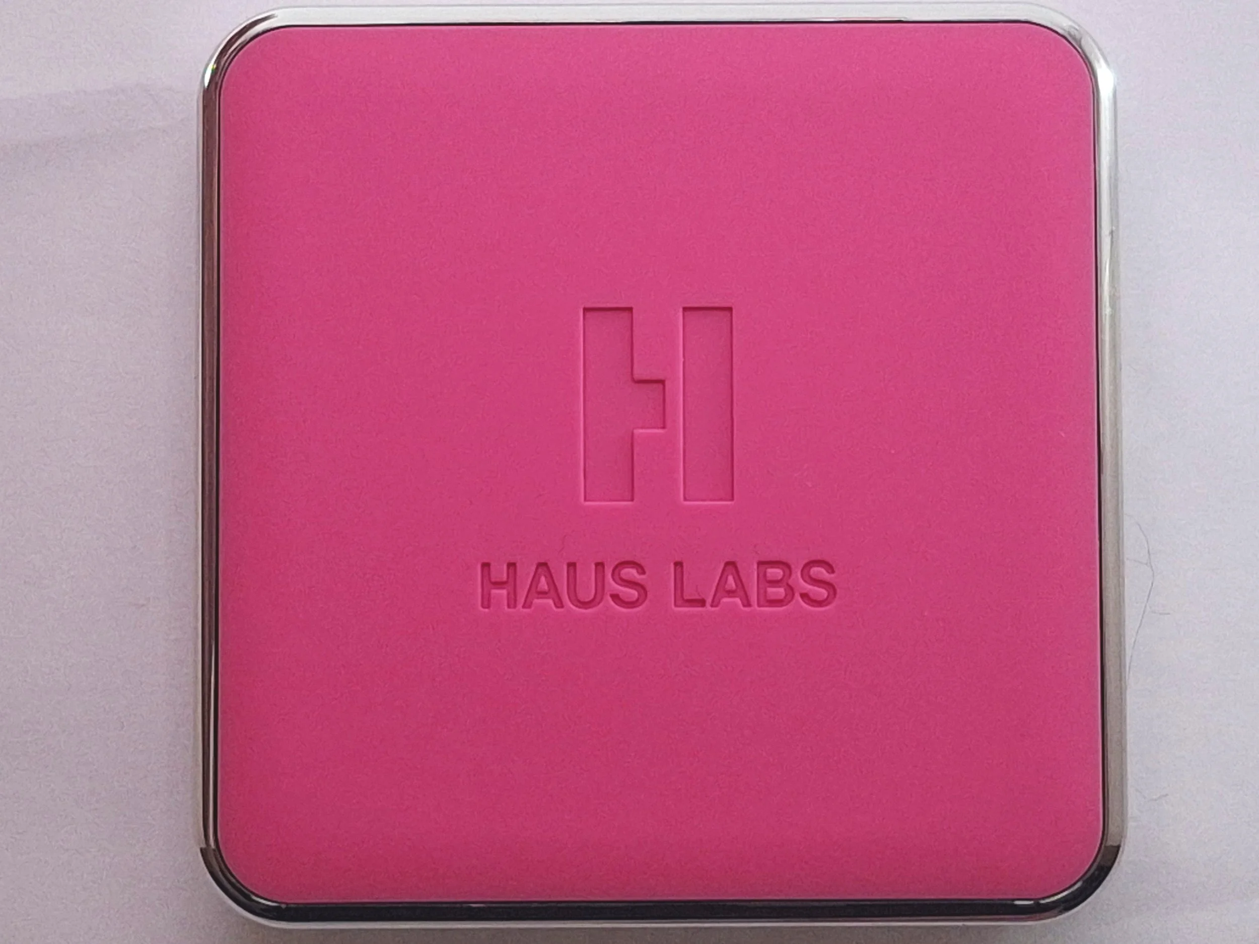 Pink square tin with a silver border, embossed with a logo and the text "HAUS LABS."