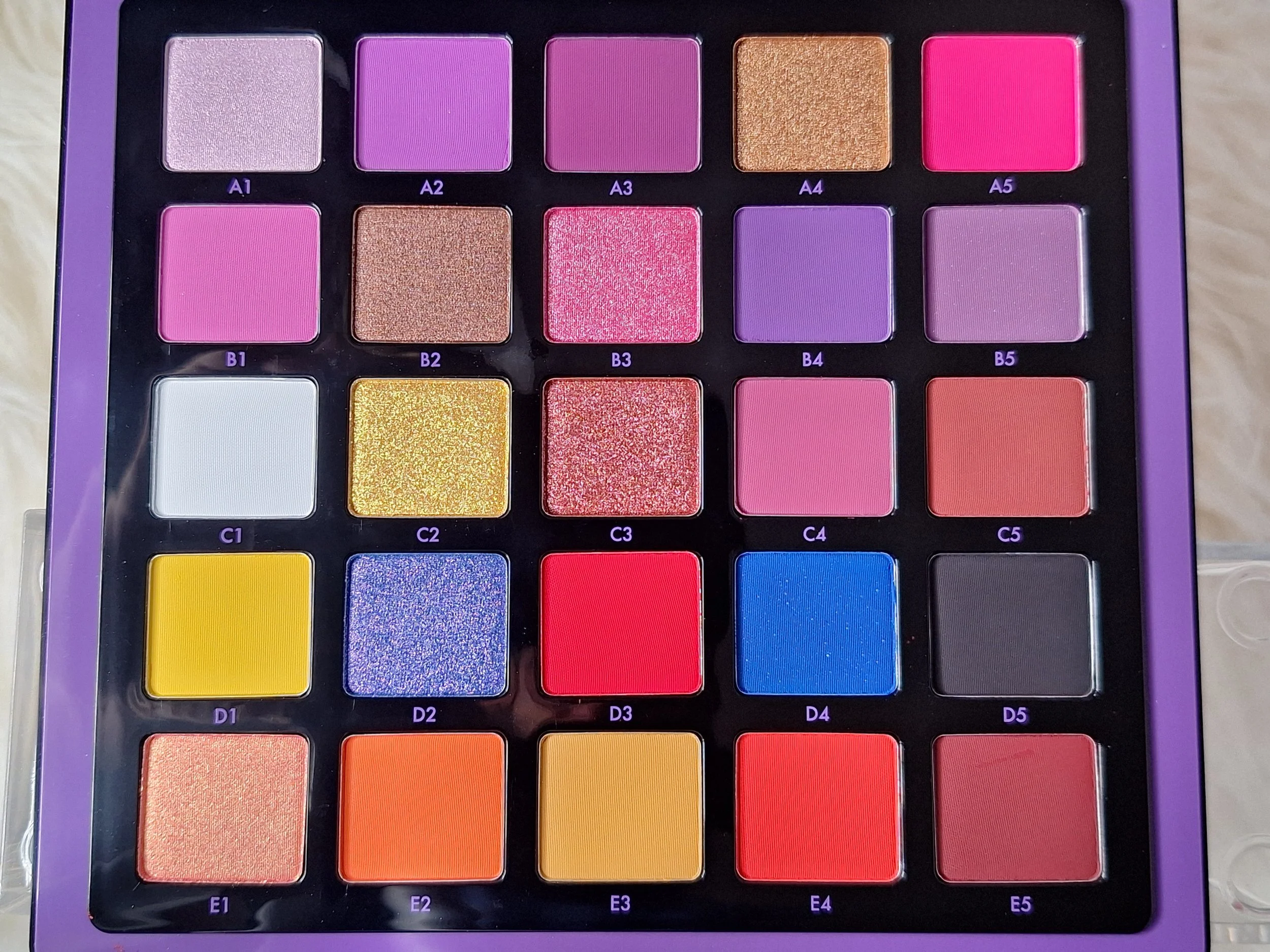 Colorful eyeshadow palette with 25 shades arranged in a 5x5 grid, including shimmery and matte finishes in various colors.