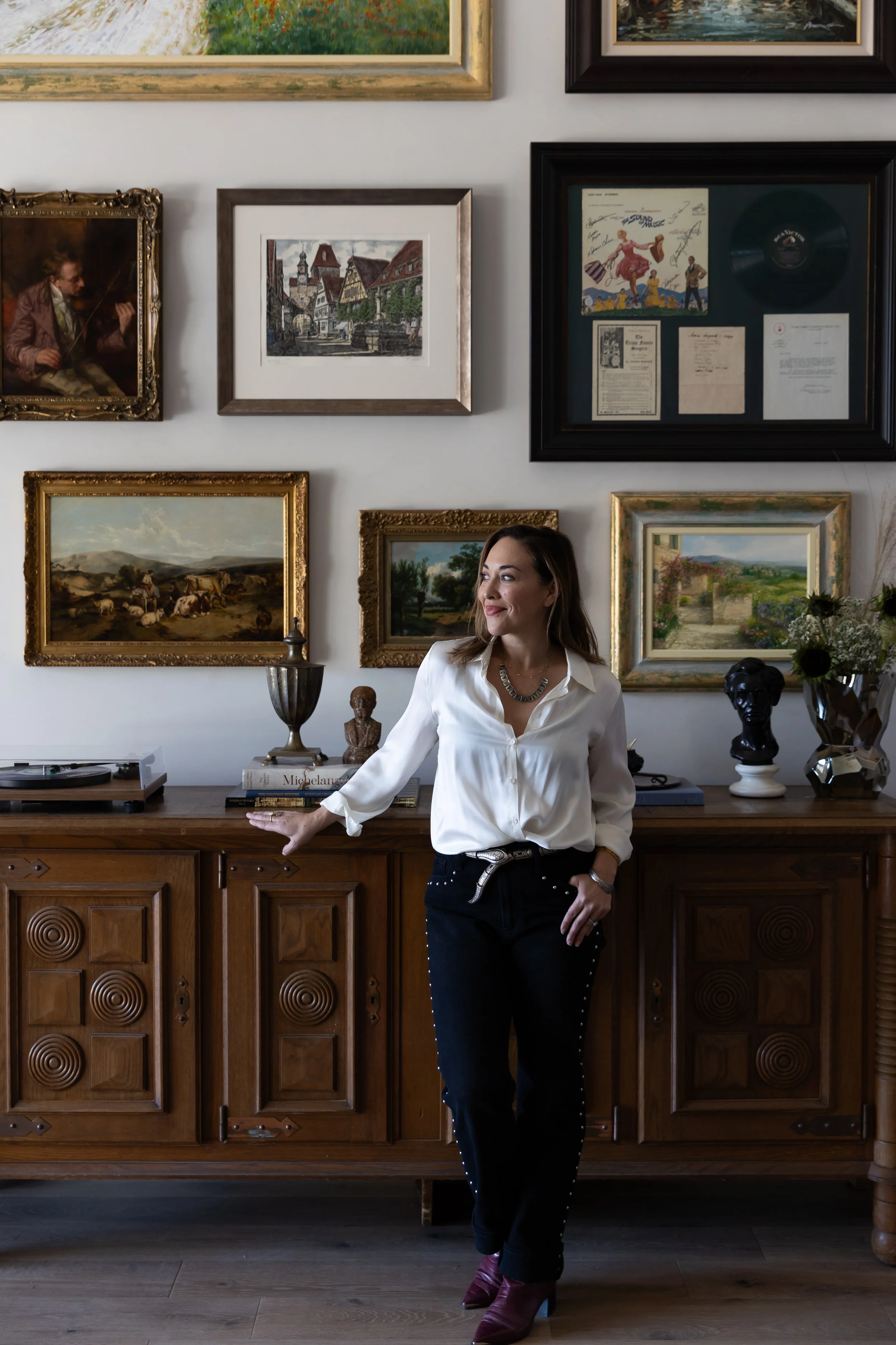 Interior designer standing in a curated room with vintage artwork and wood furniture