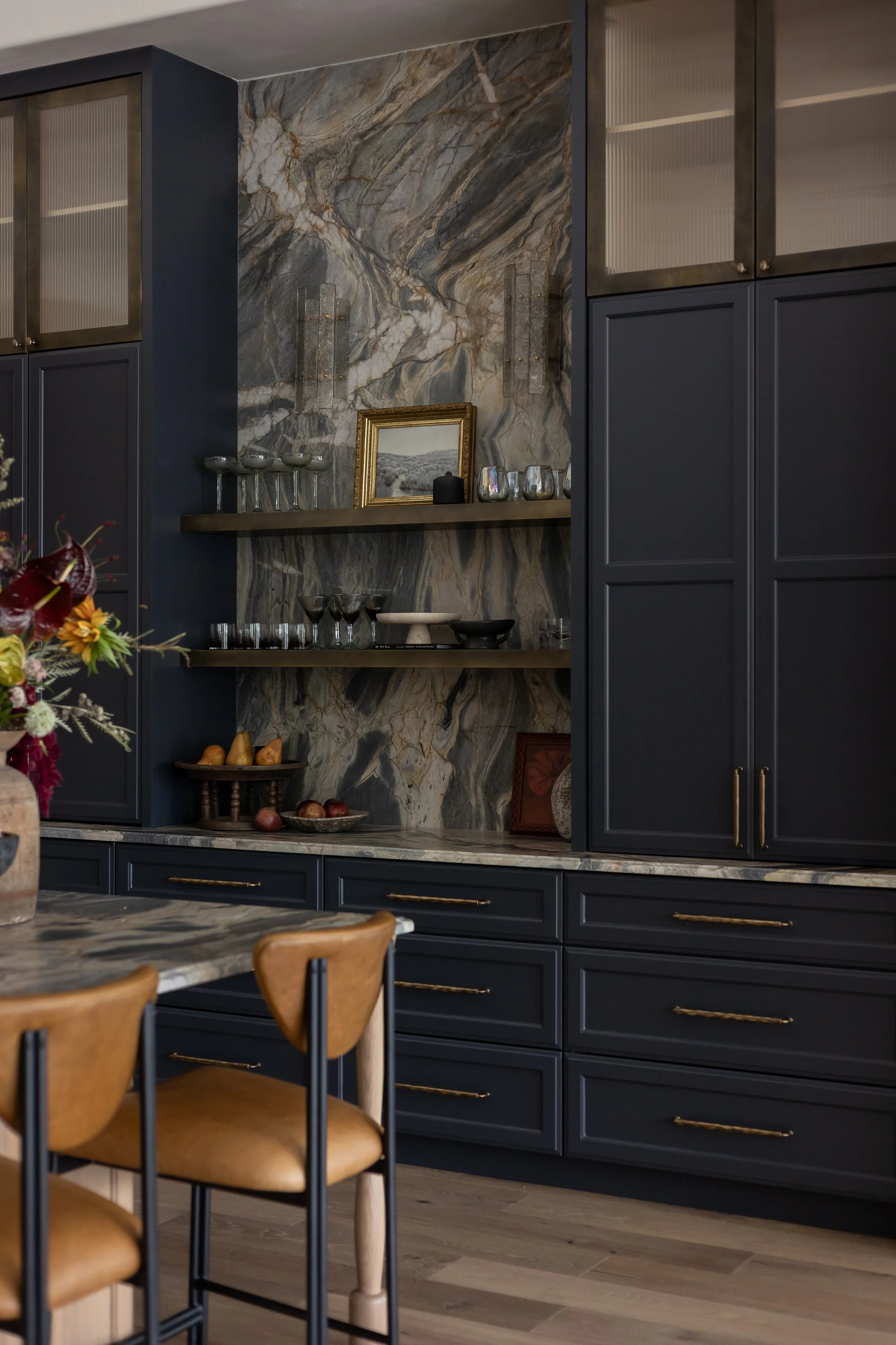 Custom kitchen with dark blue cabinetry, marble backsplash, open shelving, and brass hardware