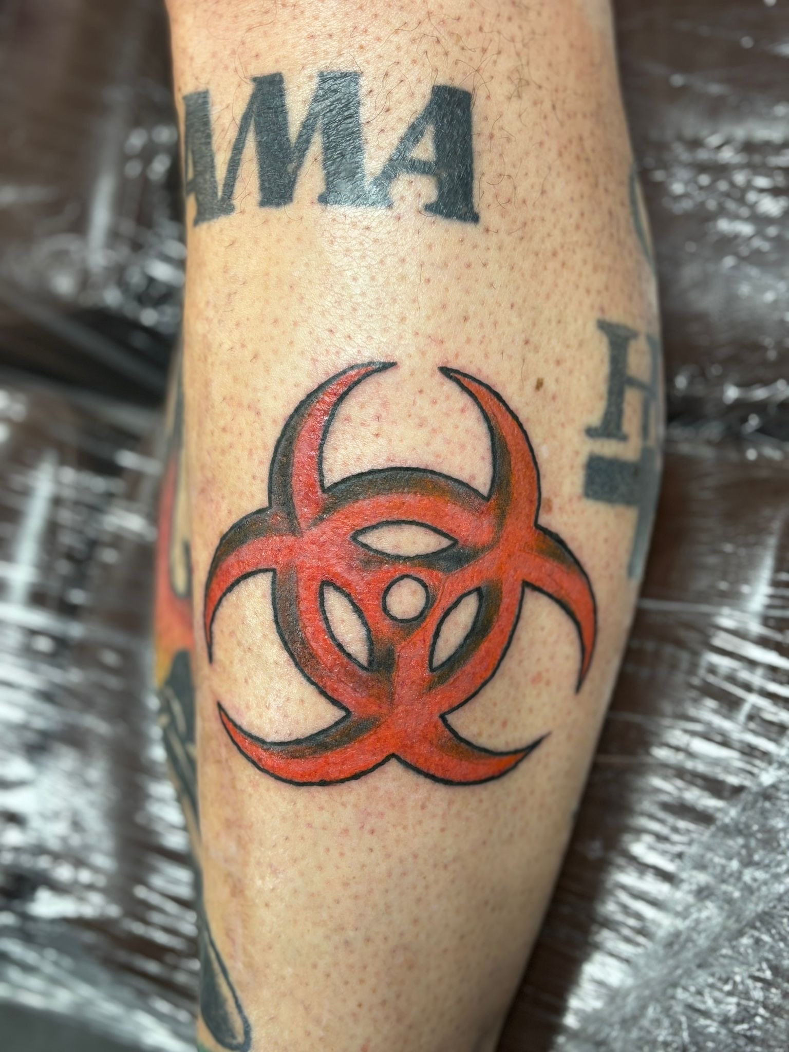 Traditional tattoo van rood cirkelvormig teken op het onderbeen, gezet door Jurjen Wielenga bij Se7en Sins Tattoo, de beste tattooshop in Friesland