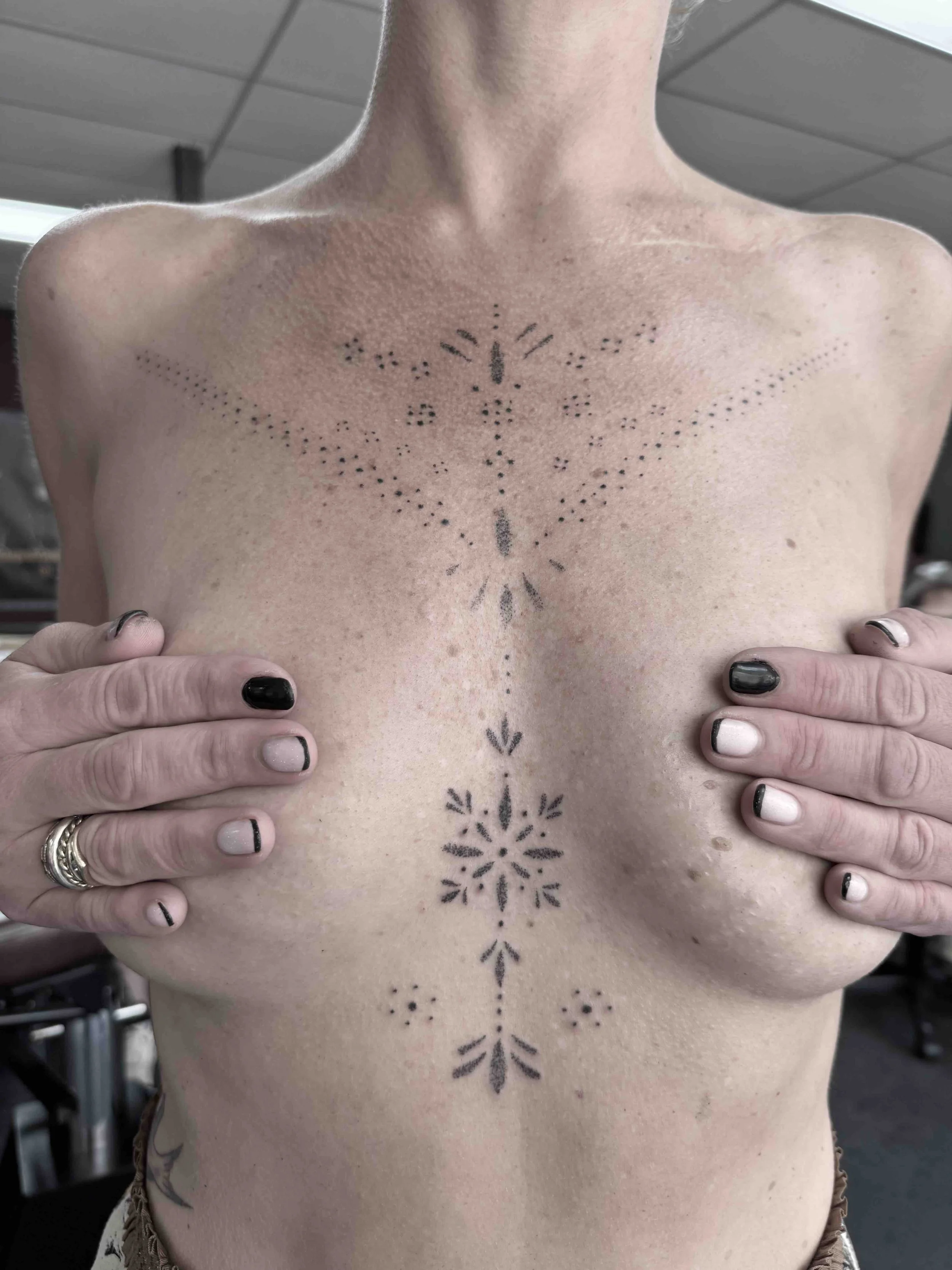 Delicate vrouwelijke handpoke tattoo rondom de borstlijn, gezet door Jenn van de Veen in Se7en Sins Tattoo, de beste tattooshop van Friesland.