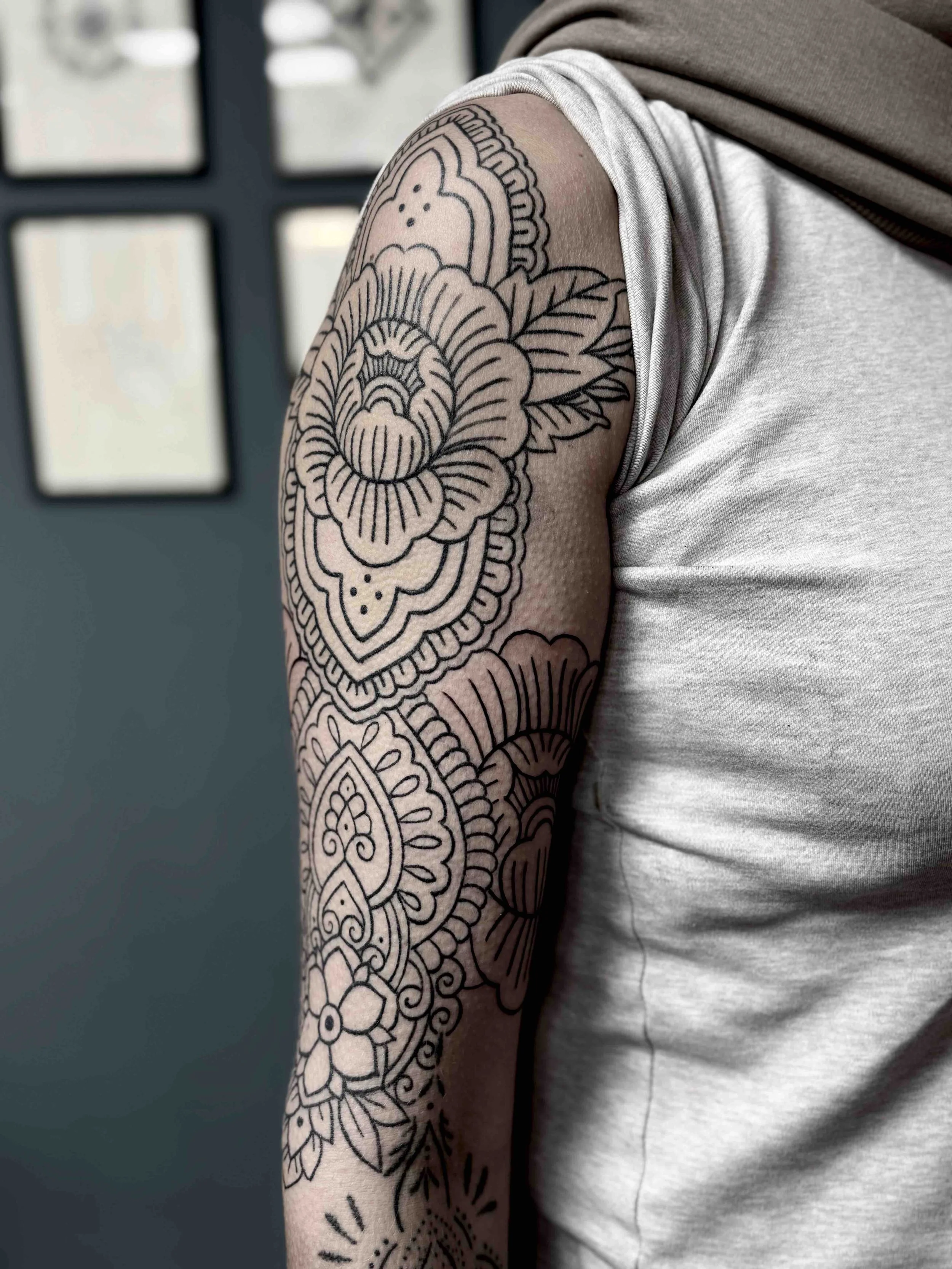 Fine line ornamental tattoo op bovenarm en schouder, ontworpen door Jenn van de Veen bij Se7en Sins Tattoo Friesland.