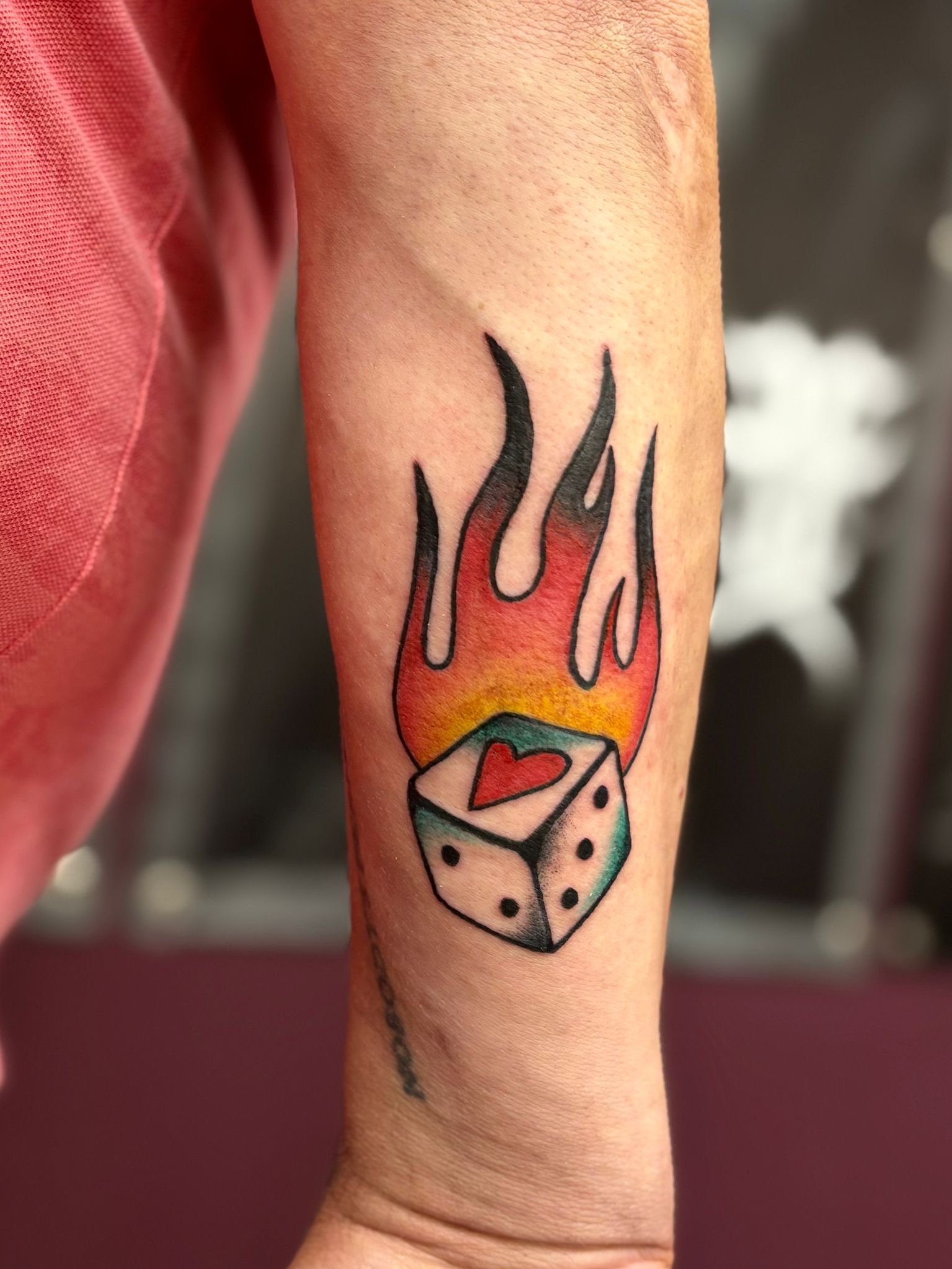 Kleurrijke old school tattoo van een dobbelsteen met hart in vlammen, ontworpen en getatoeëerd door Jurjen Wielenga bij Se7en Sins Tattoo, de beste tattoo studio in Friesland.