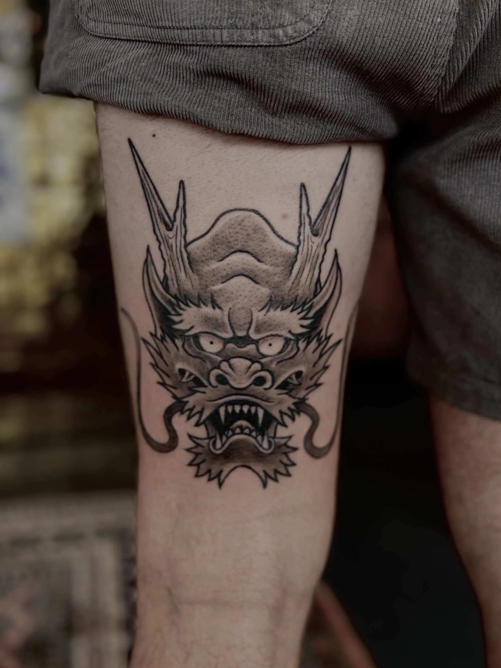 Japanse drakenkop-tattoo met hoorns op bovenbeen, vervaardigd door tattoo artist Marcel Tambach bij Se7en Sins Tattoo nabij Sneek en Lemmer.