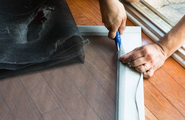 Person replacing a torn window screen on a frame