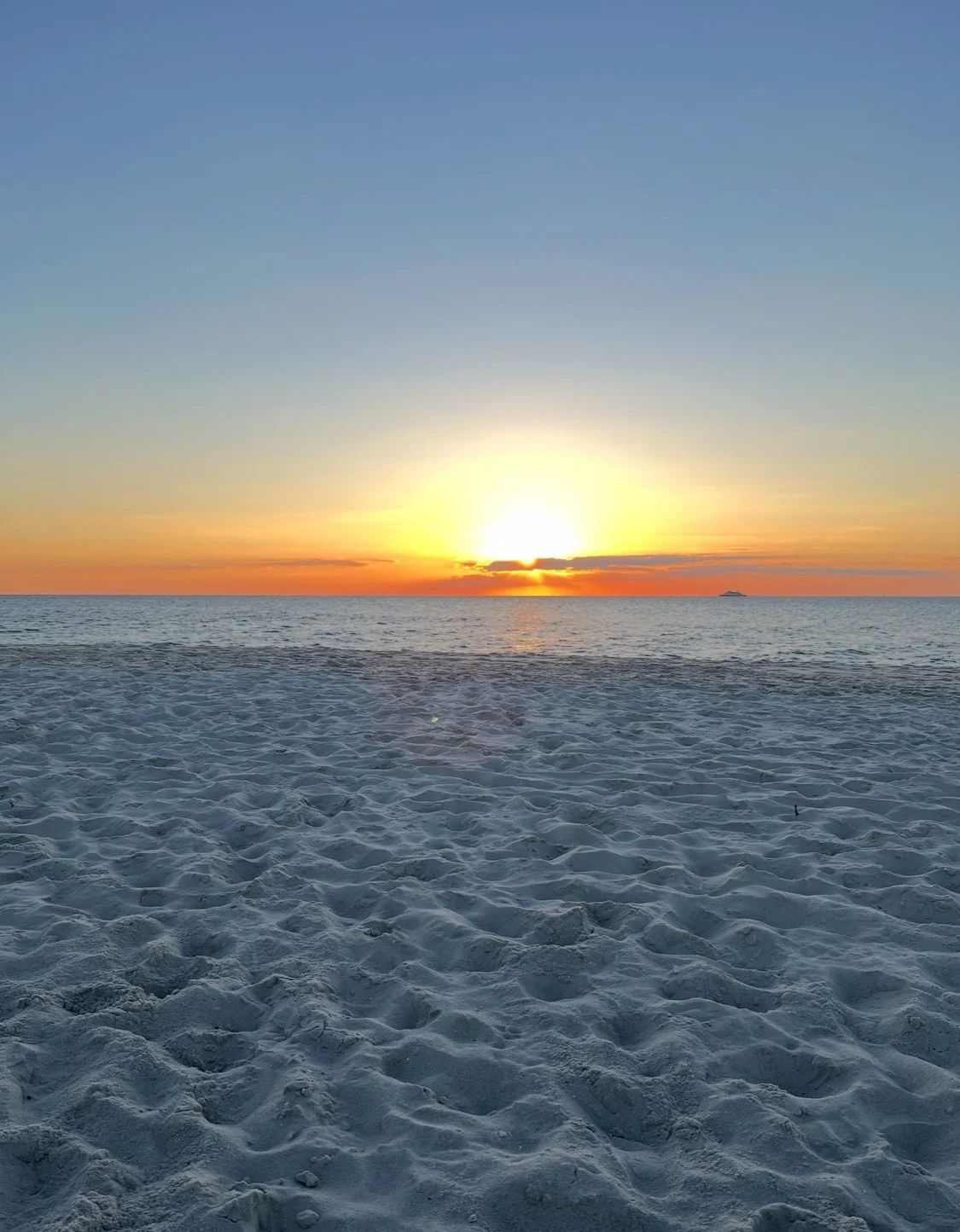 Sunset over the ocean with sandy beach in foreground