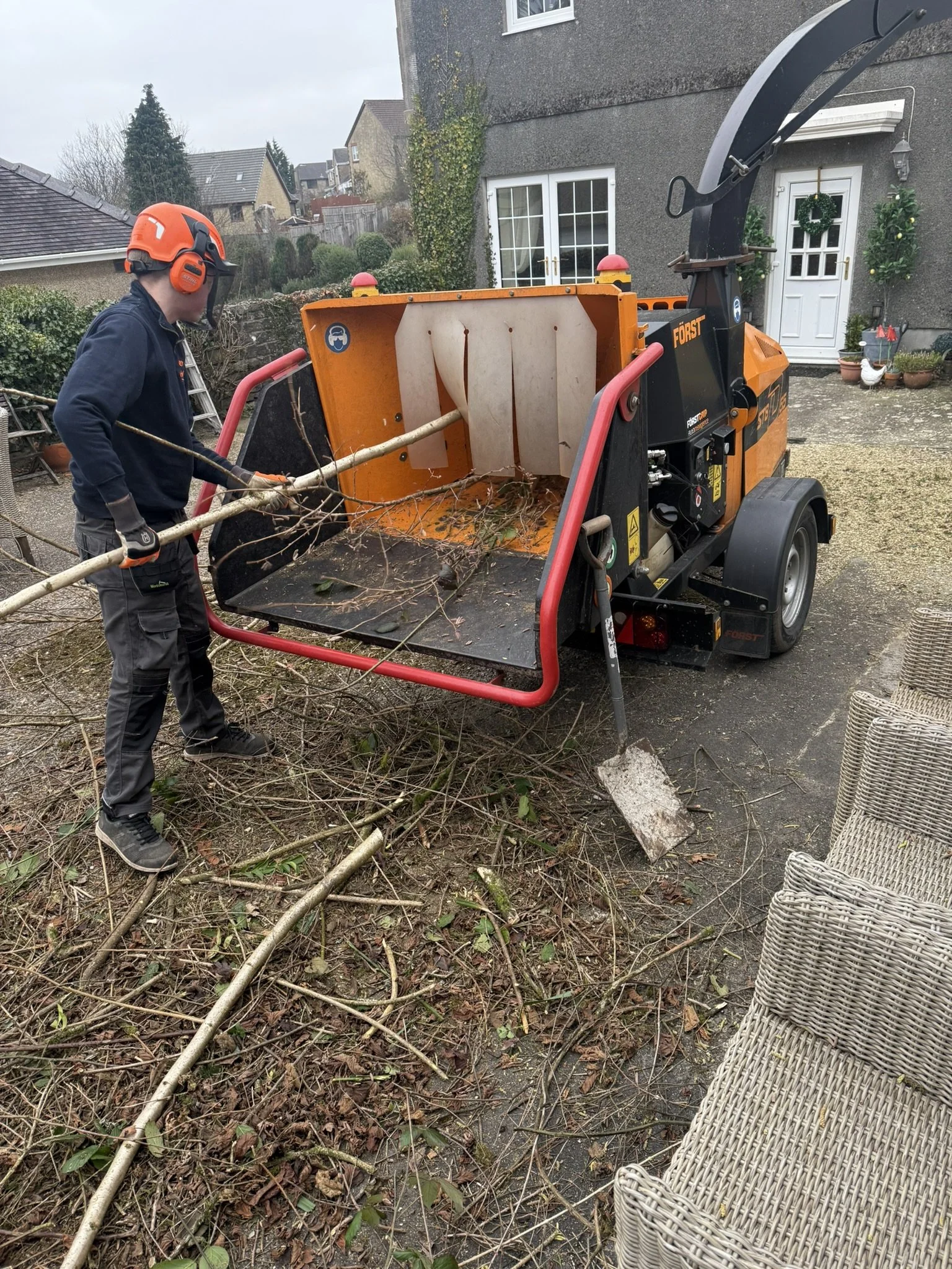 Tree surgeon feeding branches into a wood chipper on site in Swansea for Conifers From Hell