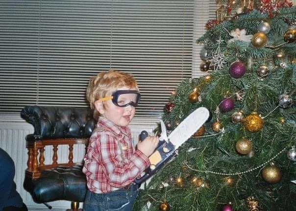 Oliver Williams as a young child holding a toy chainsaw growing up in the family tree surgery business