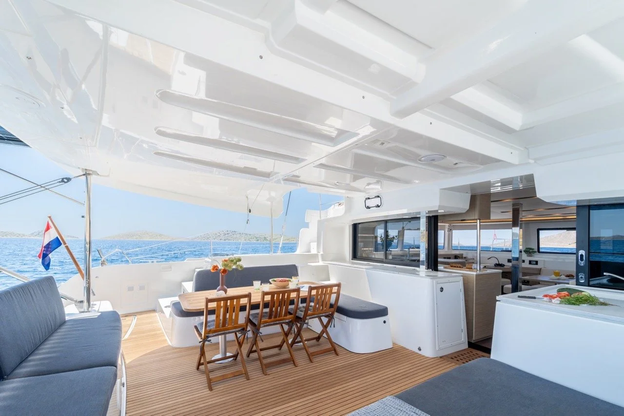 Innenansicht eines Yacht-Decks mit Essbereich, Sofa, Holzfußboden, Meerblick, Niederländischer Flagge und moderner Ausstattung.