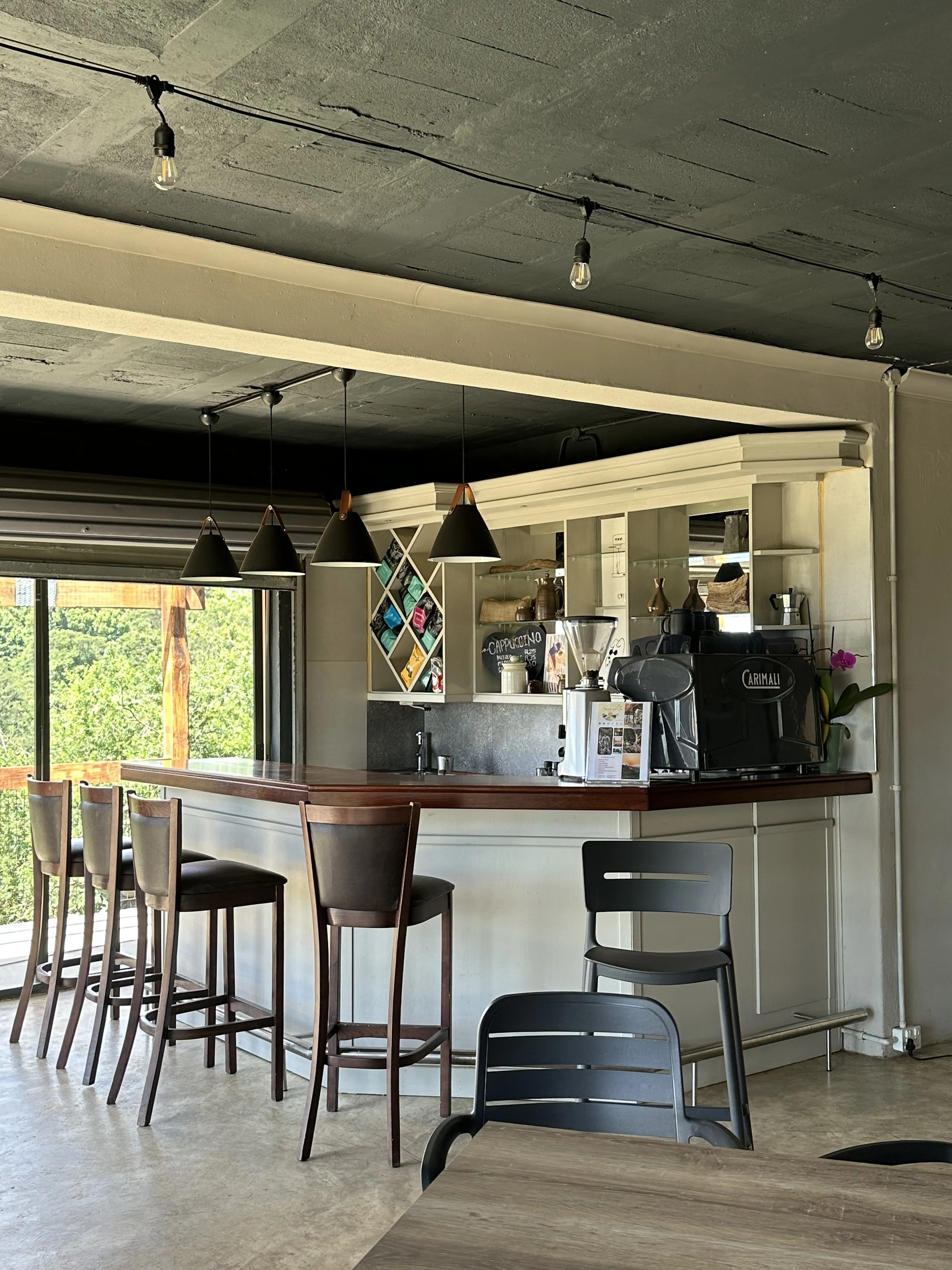 Outdoor courtyard with brick paving, wooden fence, garden beds with plants, and wall lights, surrounded by trees.