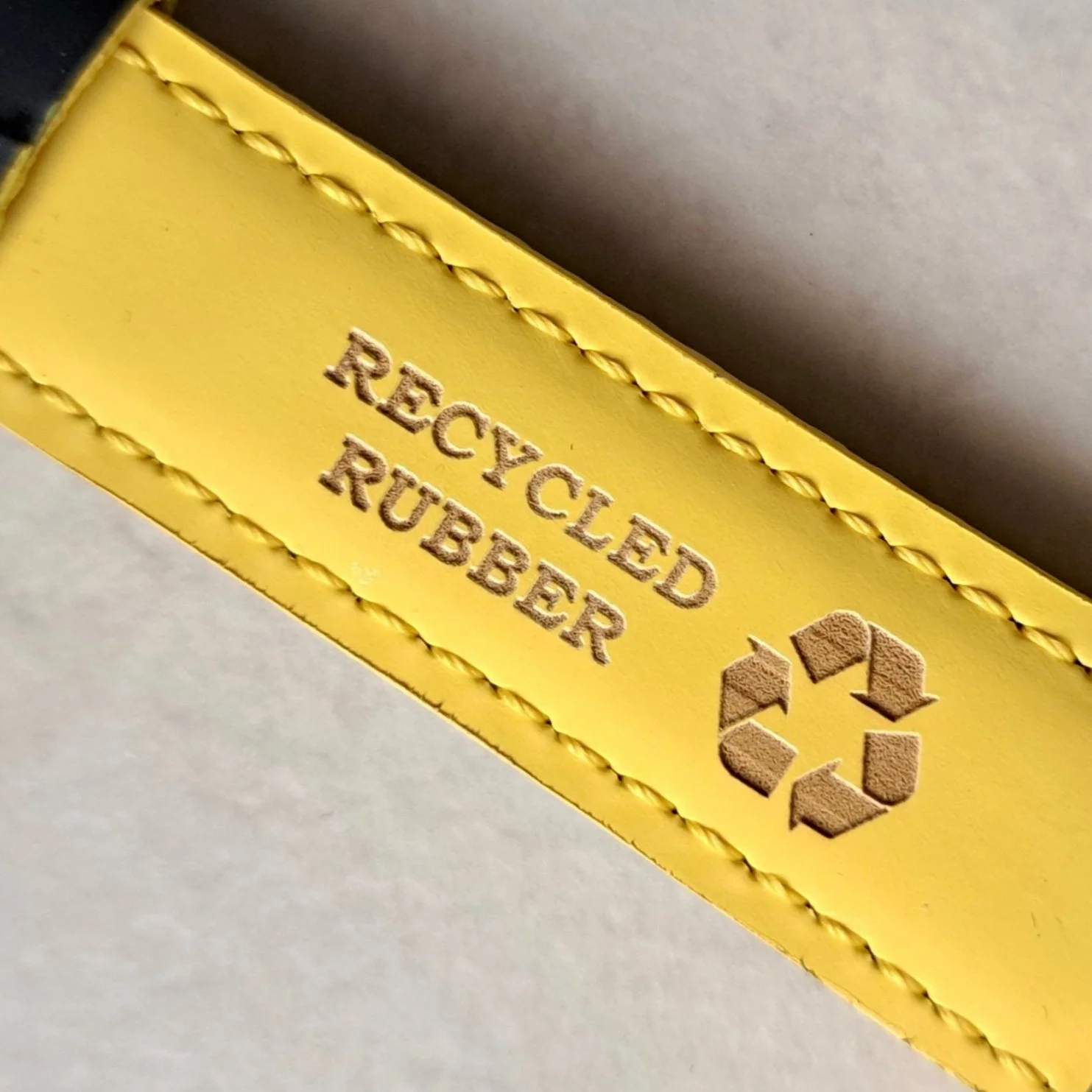 Etichetta gialla con scritte 'Recycled Rubber' e simbolo di riciclaggio.